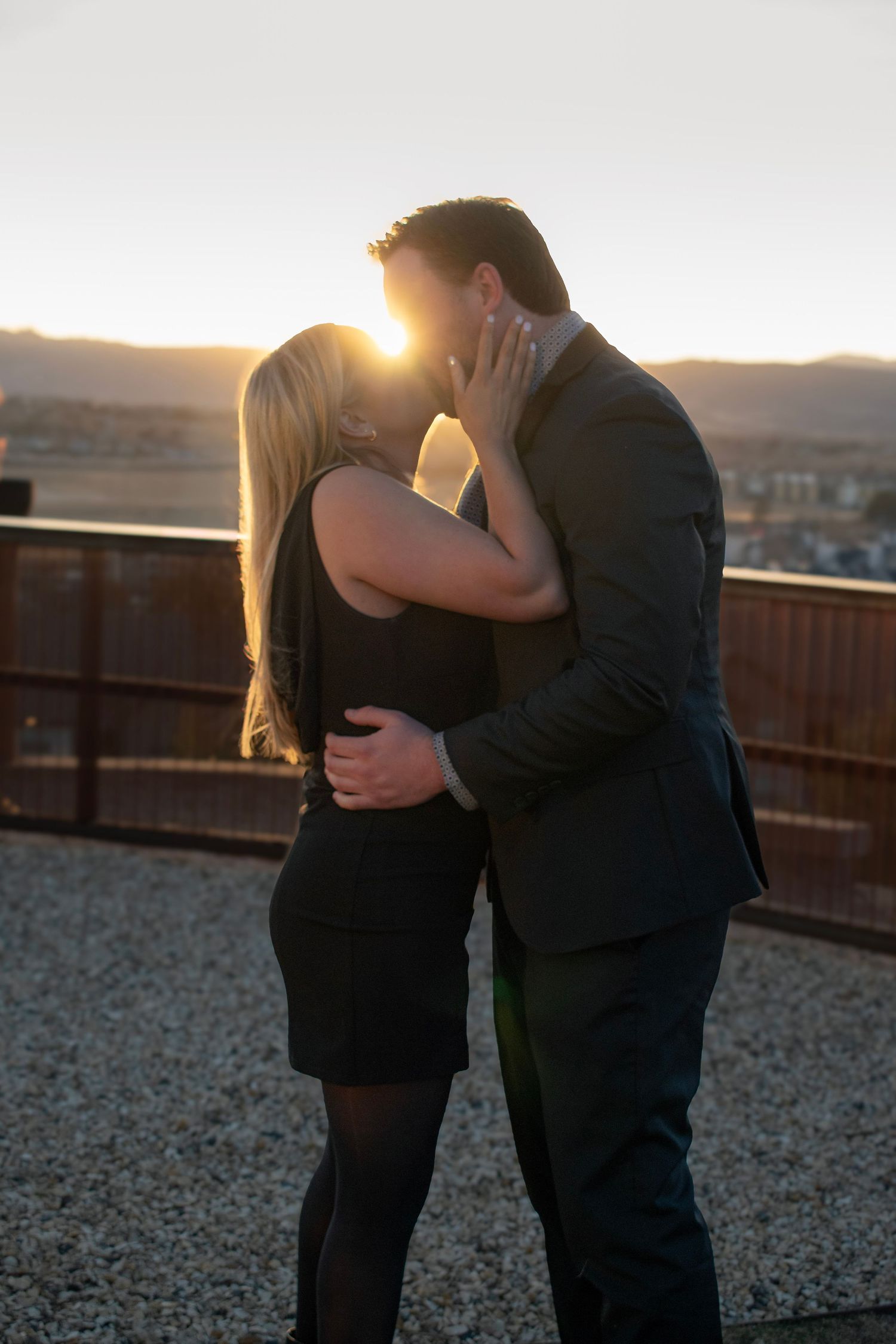 Intimate moment between couple during sunset on rooftop deck.