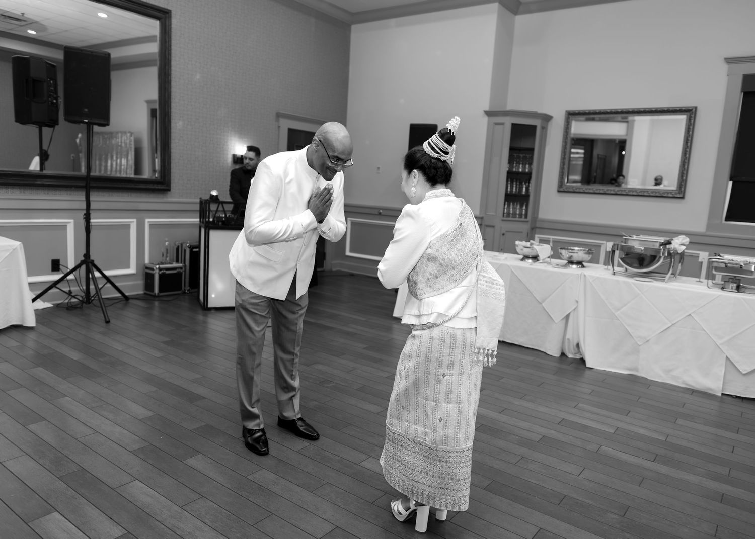 Couple sharing a graceful bow during their wedding reception dance in black and white.