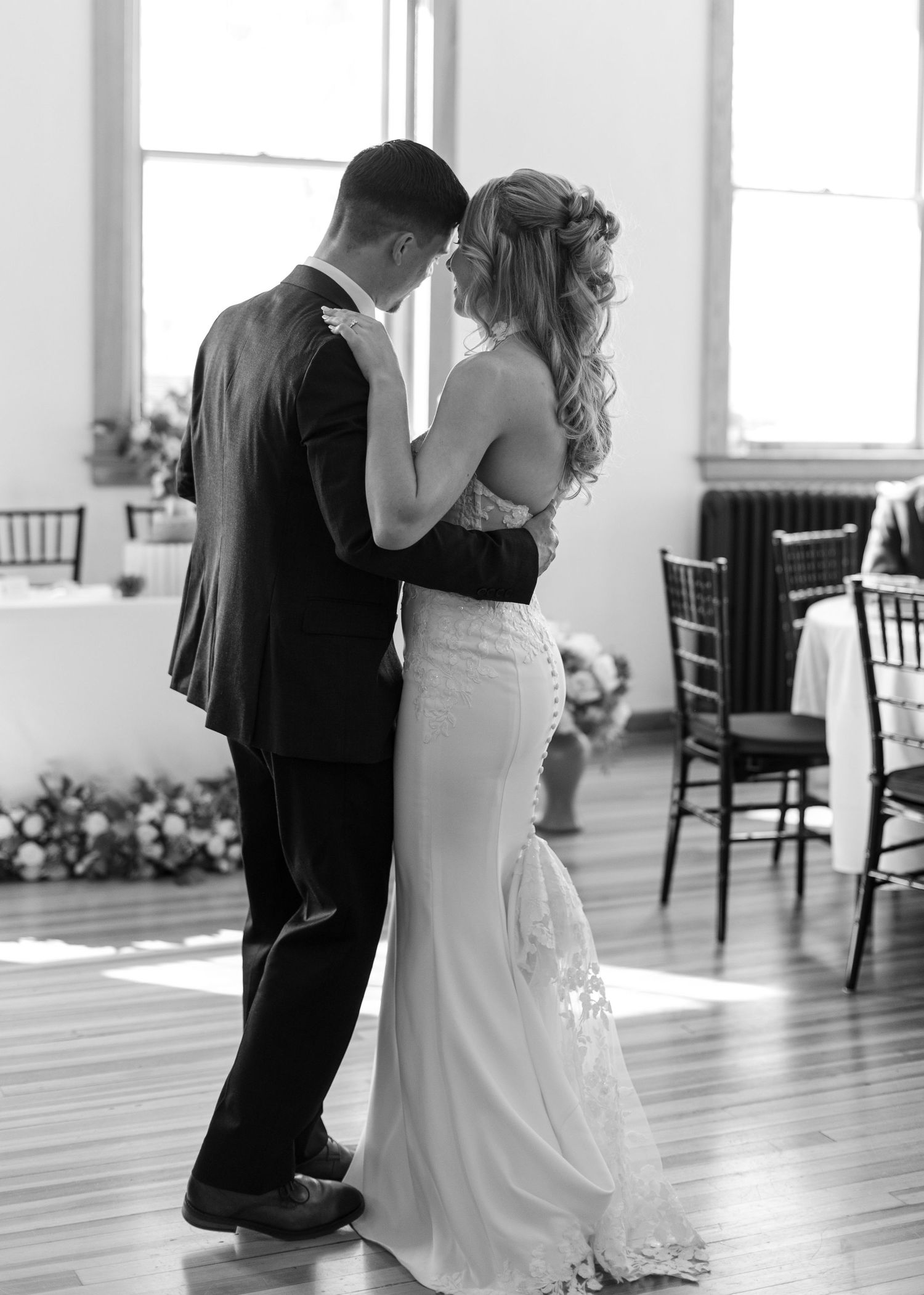 Black and white photo of bride and groom sharing their first dance at wedding reception.