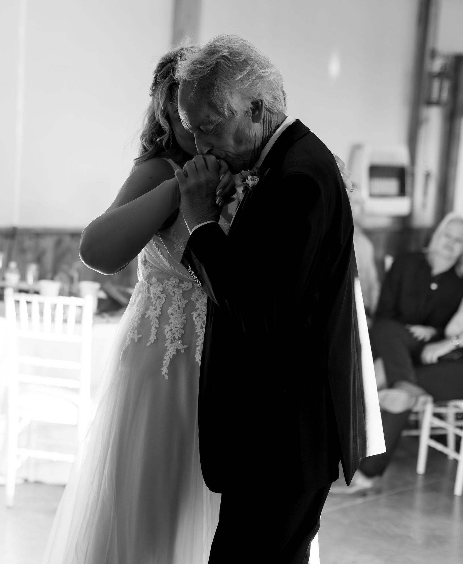 Emotional father-daughter dance at wedding reception in elegant black and white photography.