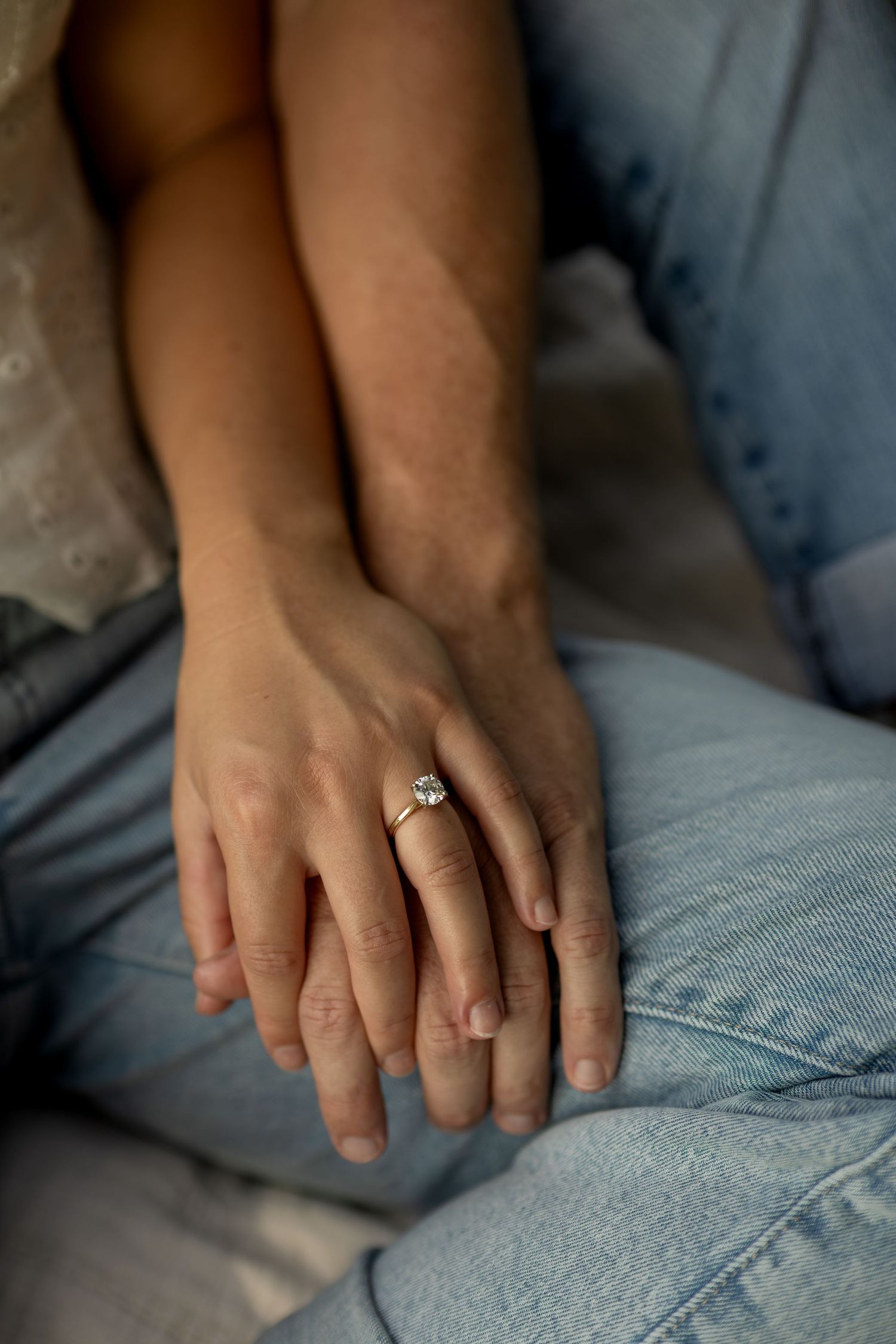 Close-up of couple's hands showing a beautiful diamond engagement ring on woman's finger.