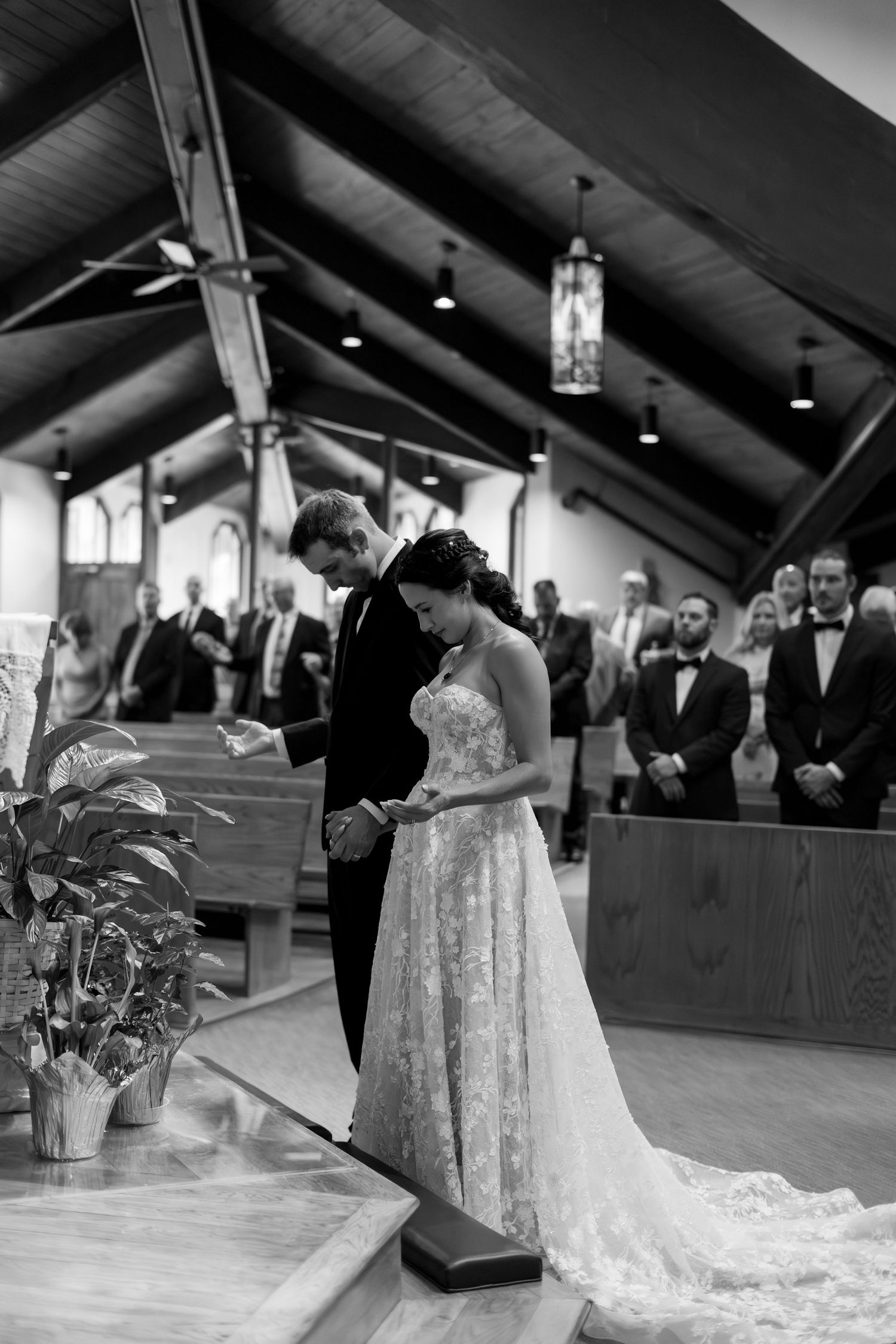 Black and white photo of bride and groom exchanging vows at church altar during wedding ceremony.