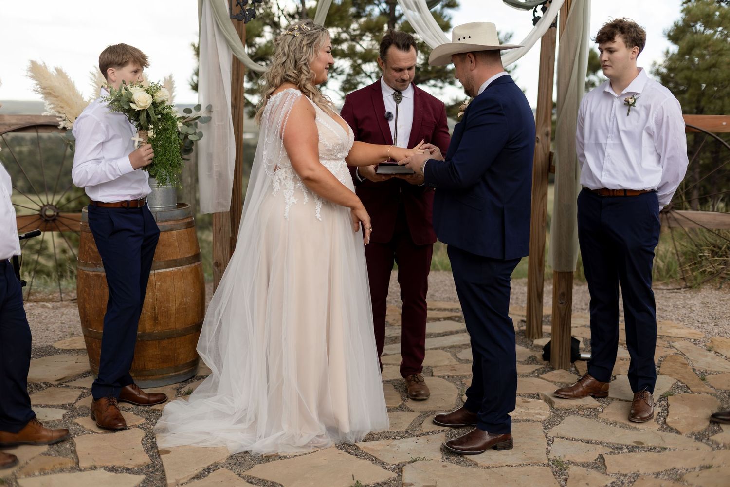 Bride and groom exchanging rings at rustic outdoor wedding ceremony.
