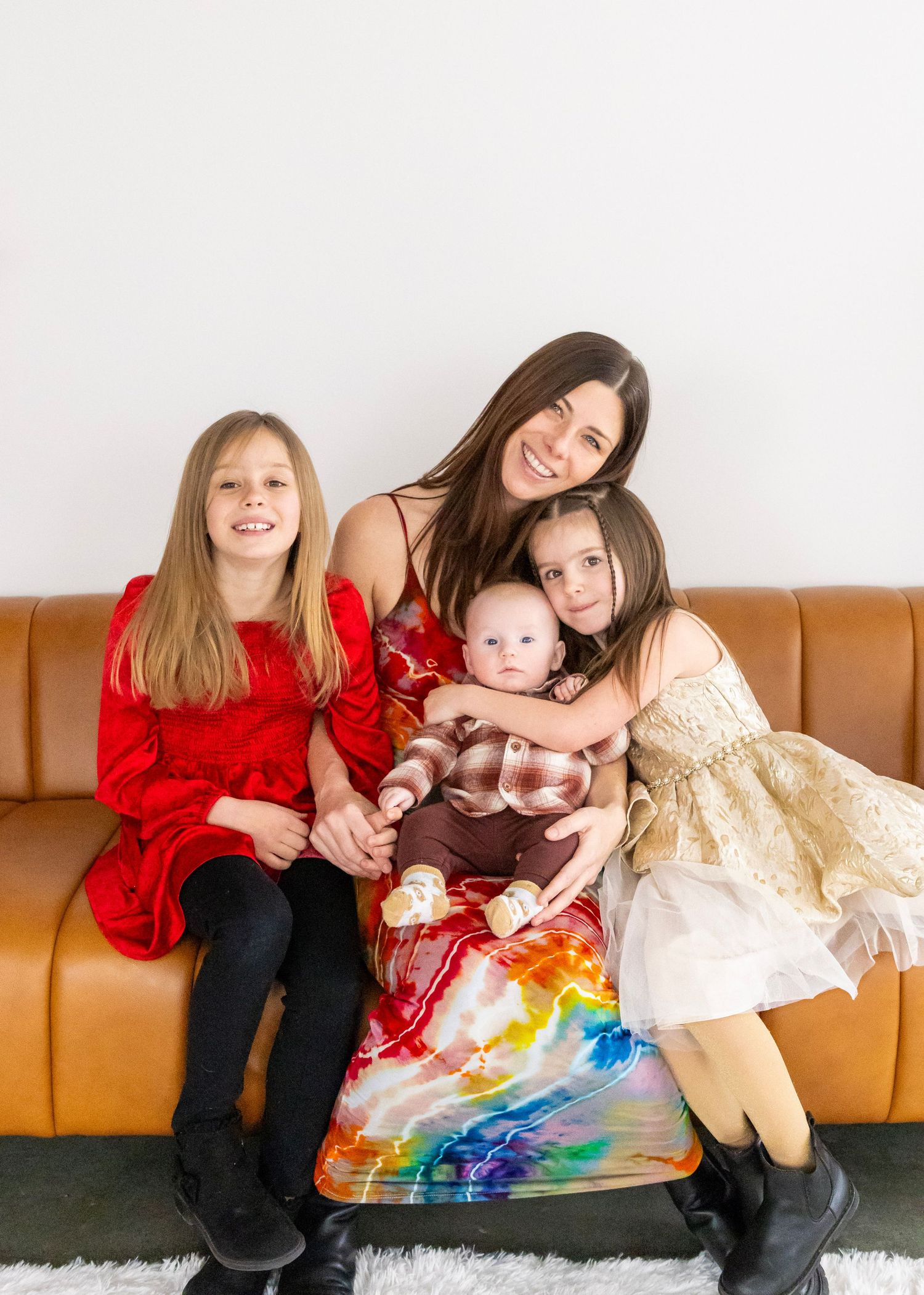 A series of four photos showing a family relaxing together on a brown leather couch with a colorful rainbow blanket.