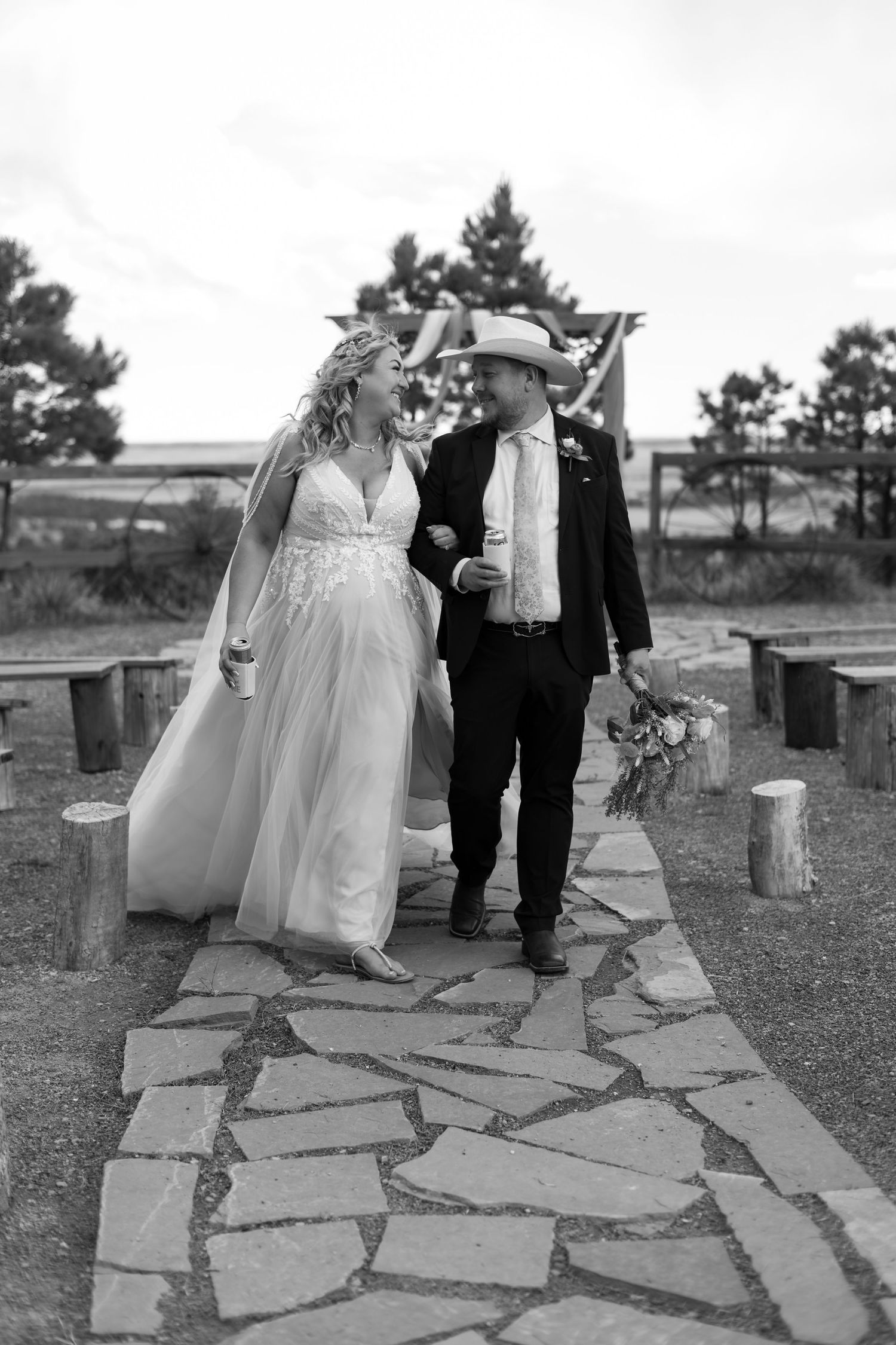 Bride and groom walking together on stone path at outdoor wedding venue in black and white.