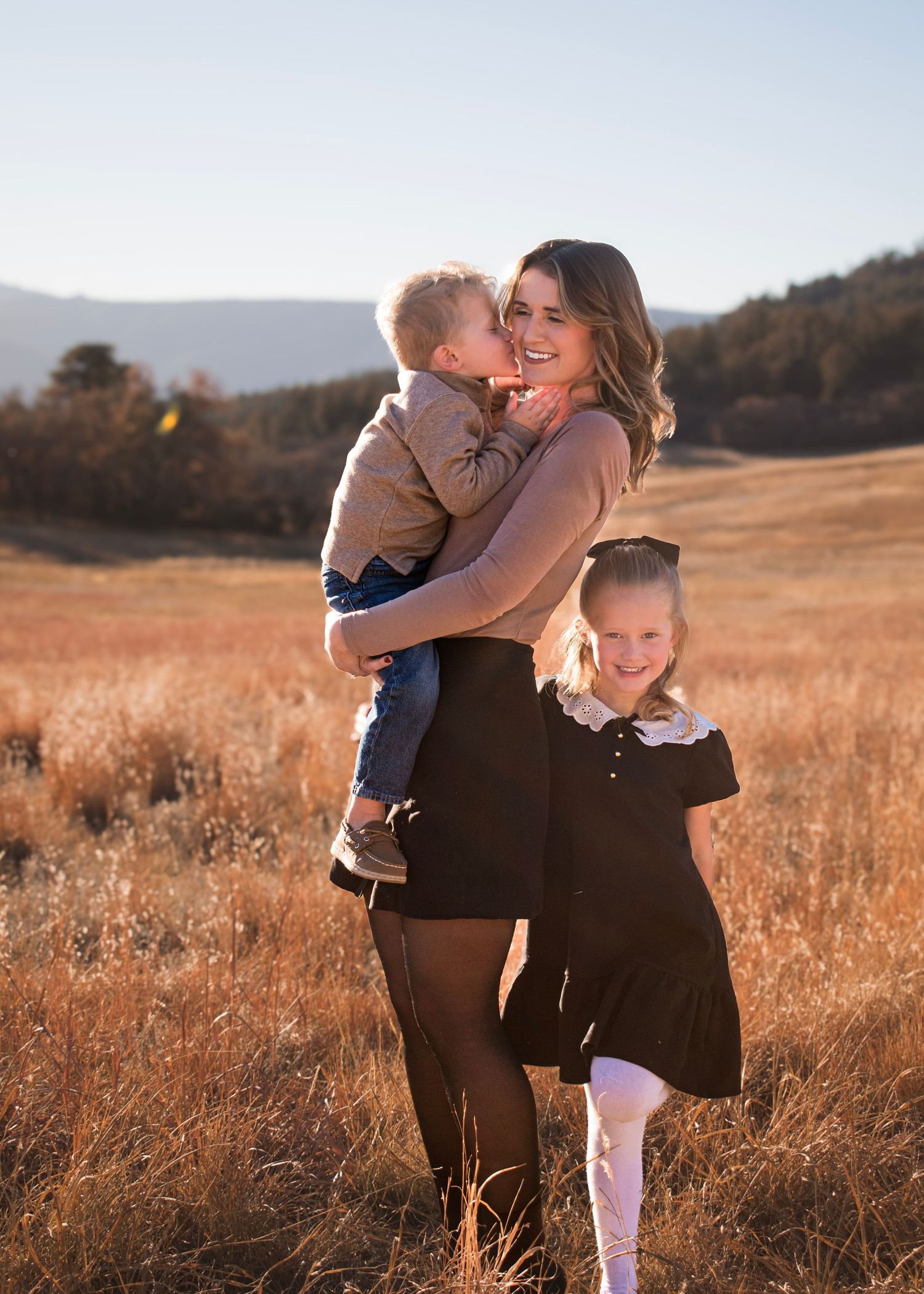 A family shares tender moments in a golden field during sunset.