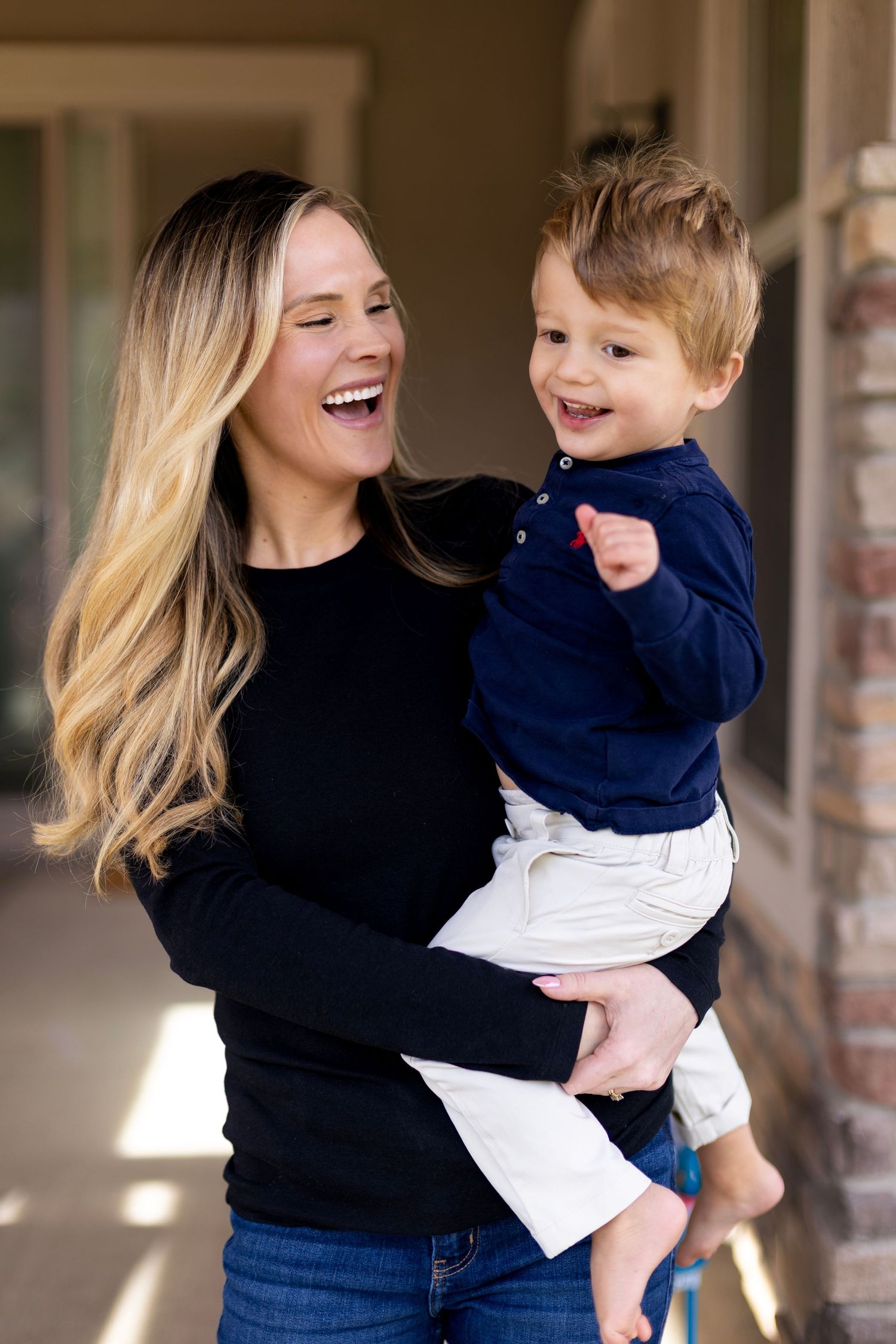 A series of candid photos showing a parent in a navy sweater holding and playing with a small child in a navy outfit.