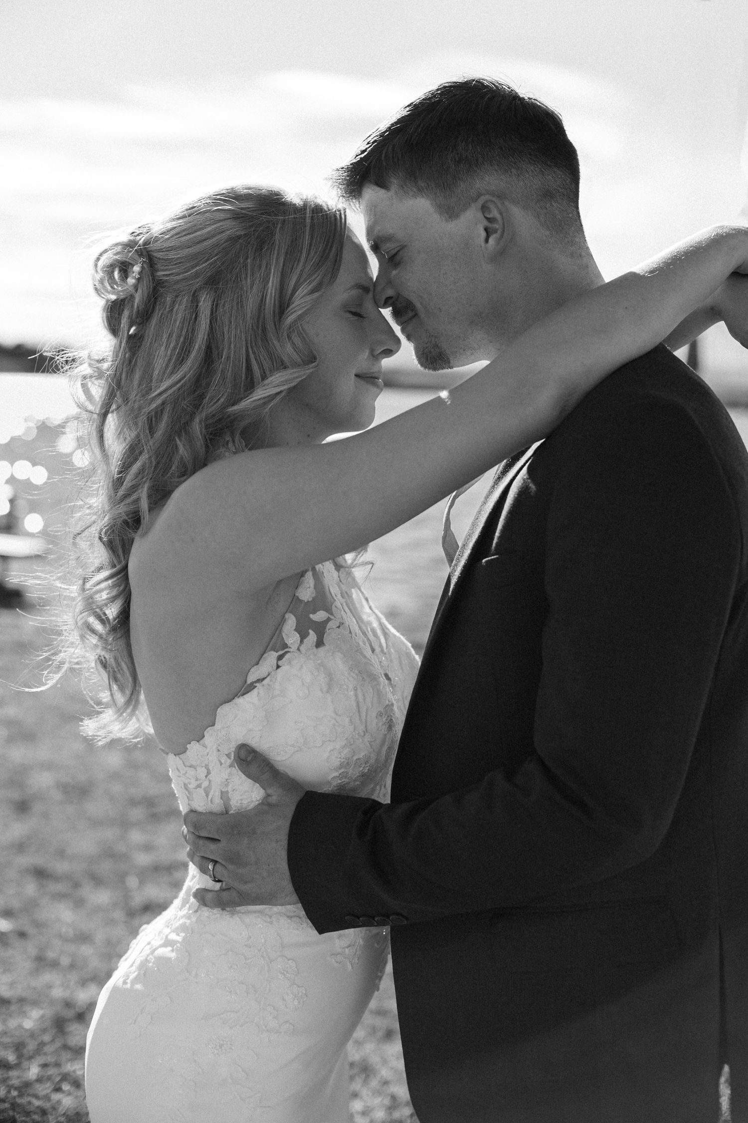 A romantic black and white wedding photo series showing a couple sharing intimate kisses in an outdoor setting.