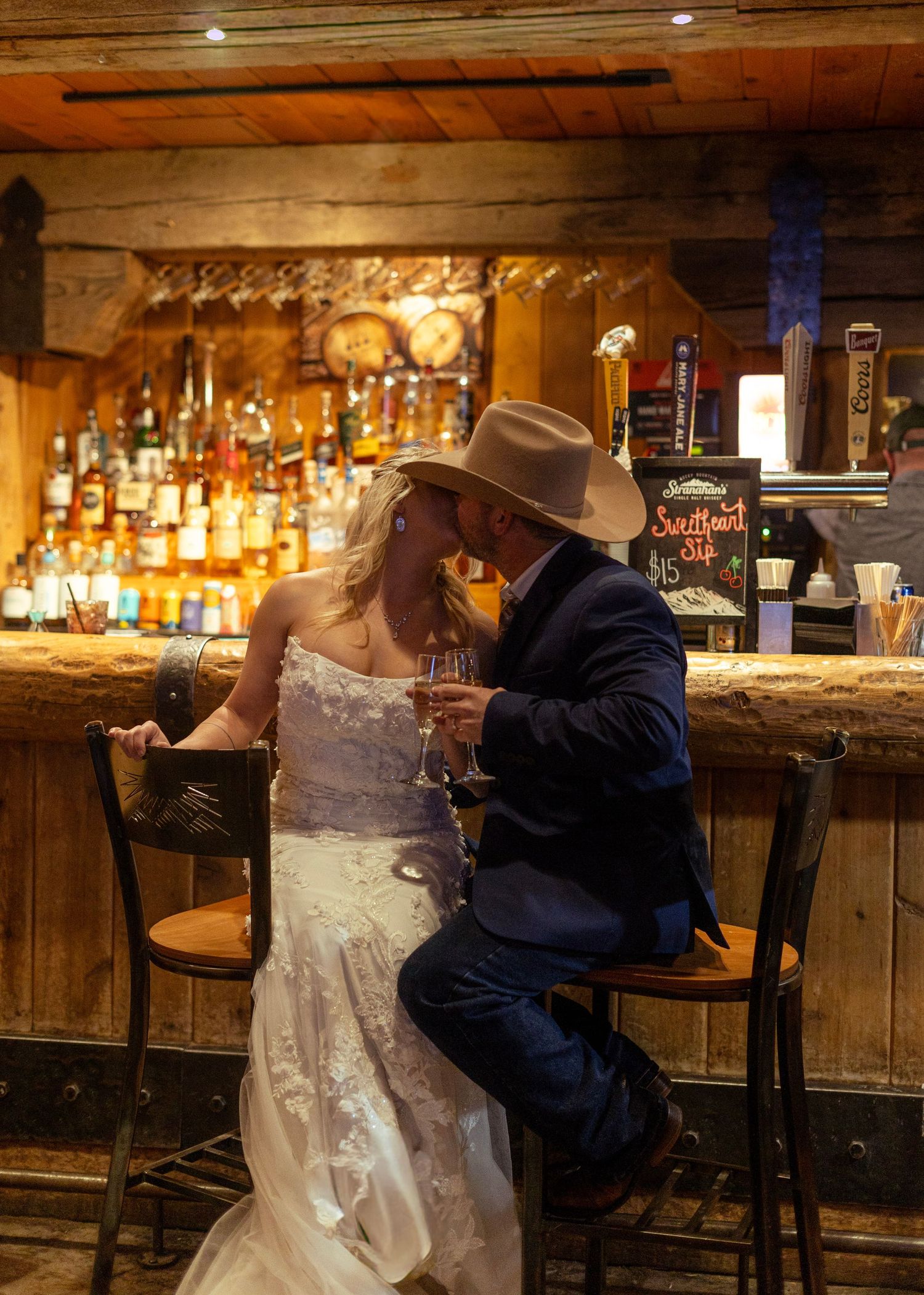 A romantic couple shares a tender dance moment in a rustic bar setting with warm lighting and wooden decor.