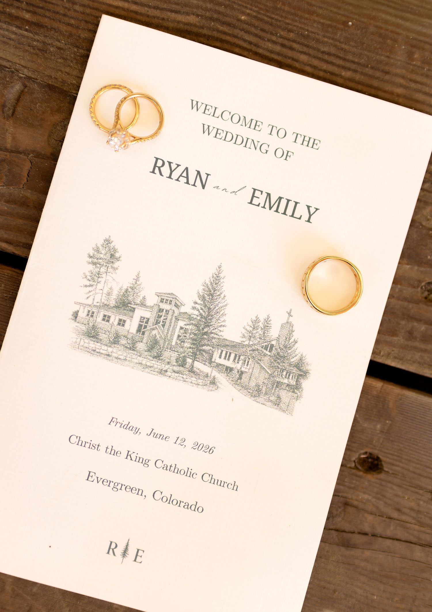 Wedding program for Ryan and Emily at Christ the King Catholic Church in Evergreen, Colorado, with gold rings on top.