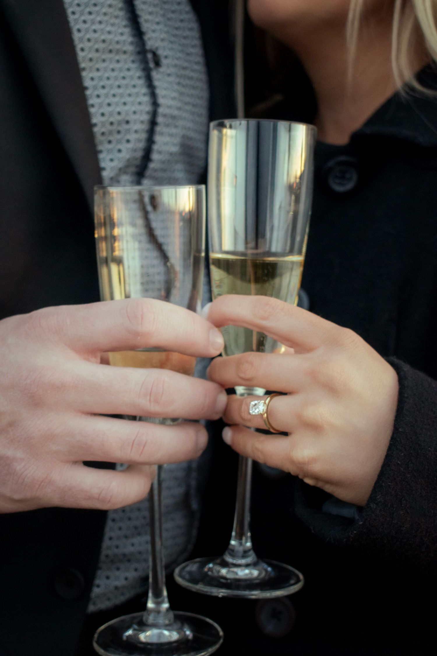 Close up of champagne toast showing engagement ring and glasses.