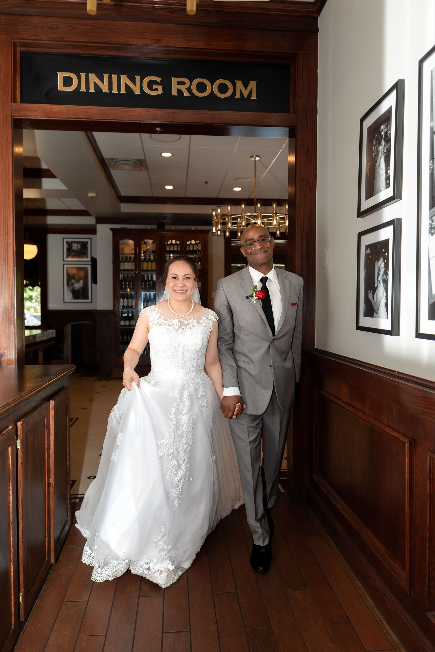 Newlywed couple walks hand-in-hand through dining room entrance at wedding reception venue smiling joyfully.