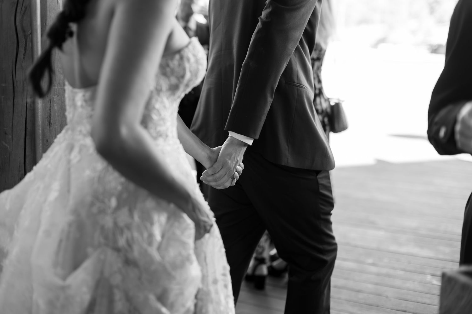 Black and white photo of a bride and groom holding hands at their wedding ceremony.