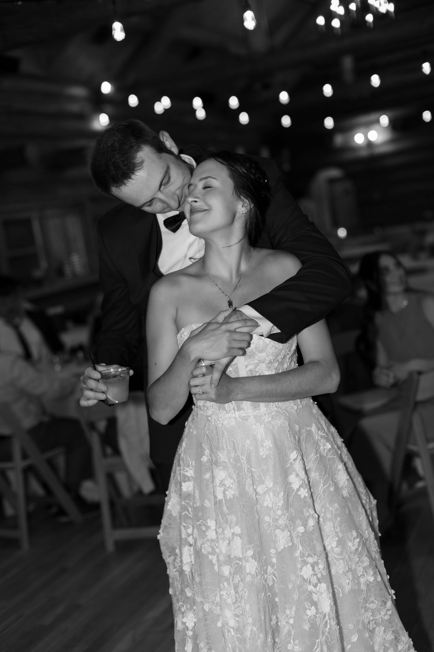 Black and white photo of a bride and groom sharing a romantic first dance at their wedding reception.