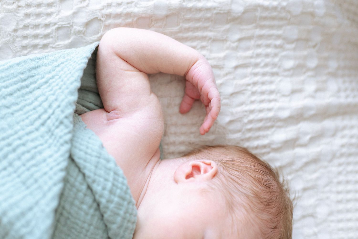 A series of images showing a baby sleeping peacefully on white bedding with a mint green blanket.