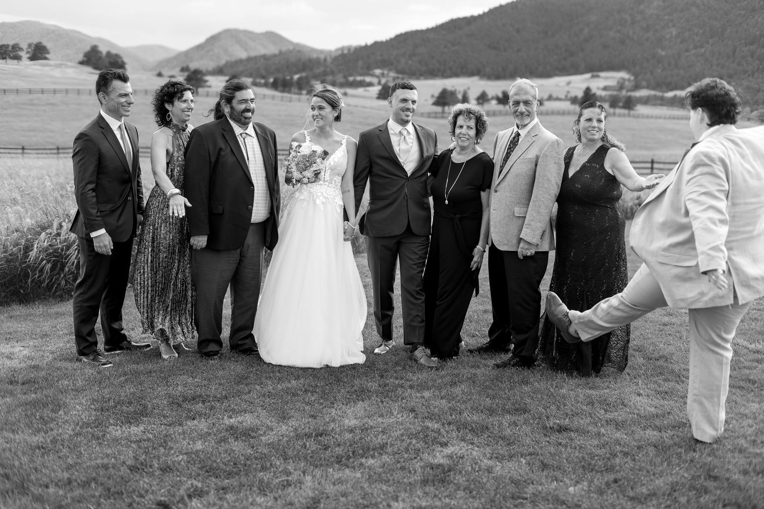 Wedding party group portrait outdoors with mountains in background in black and white photo.