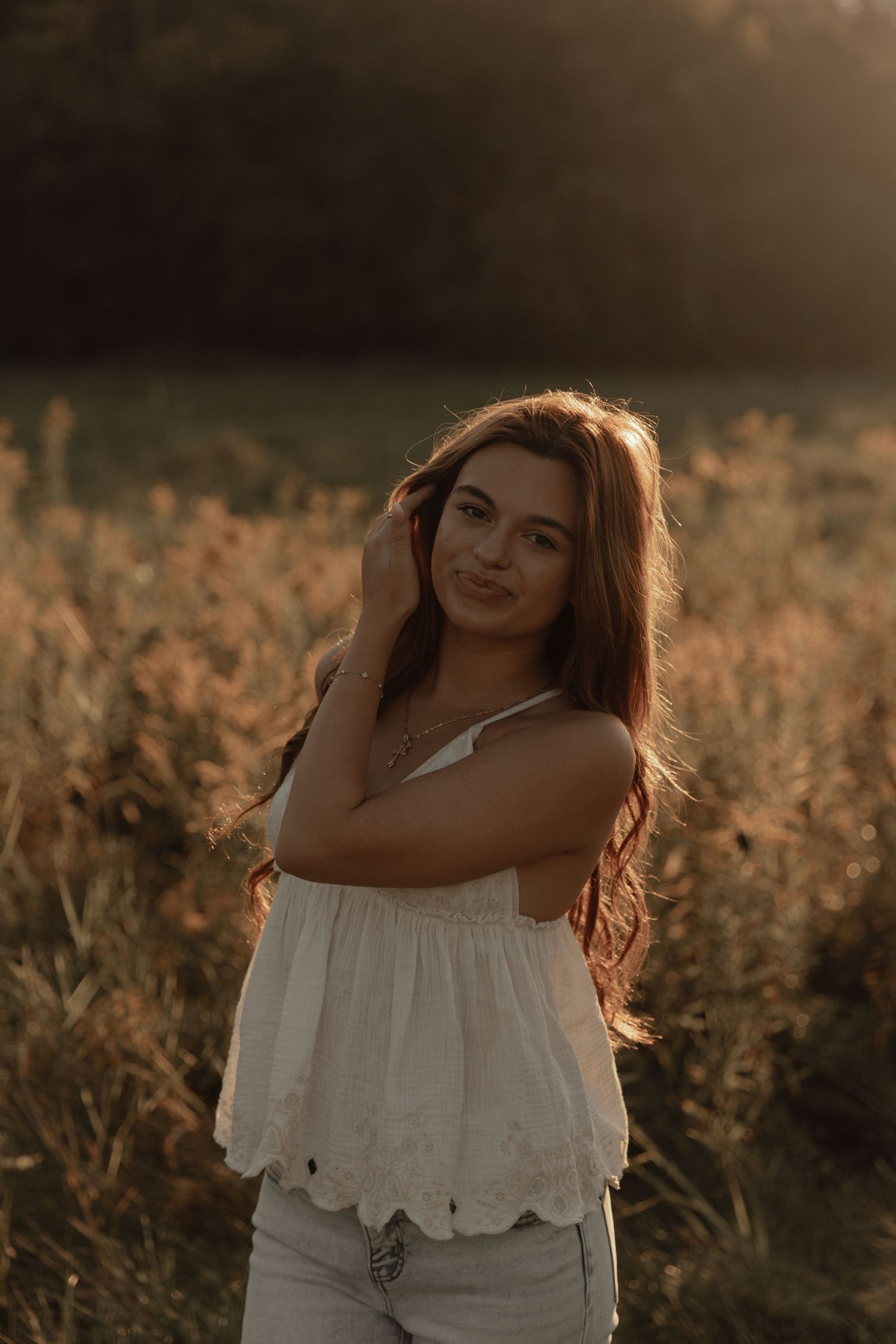 Golden hour portrait in a field with tall grass and warm sunset lighting.