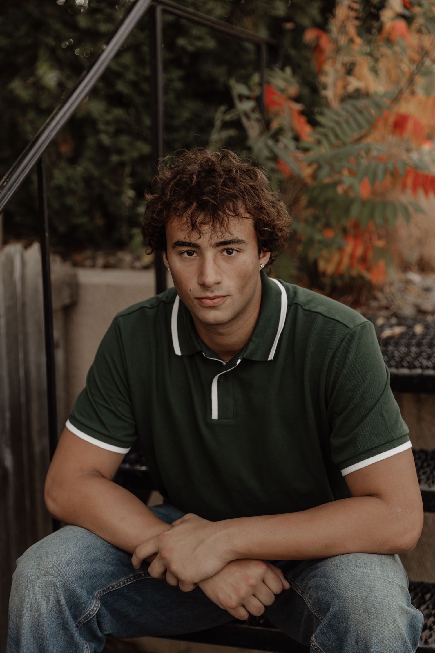 Outdoor portrait of someone in a green polo shirt sitting on steps.