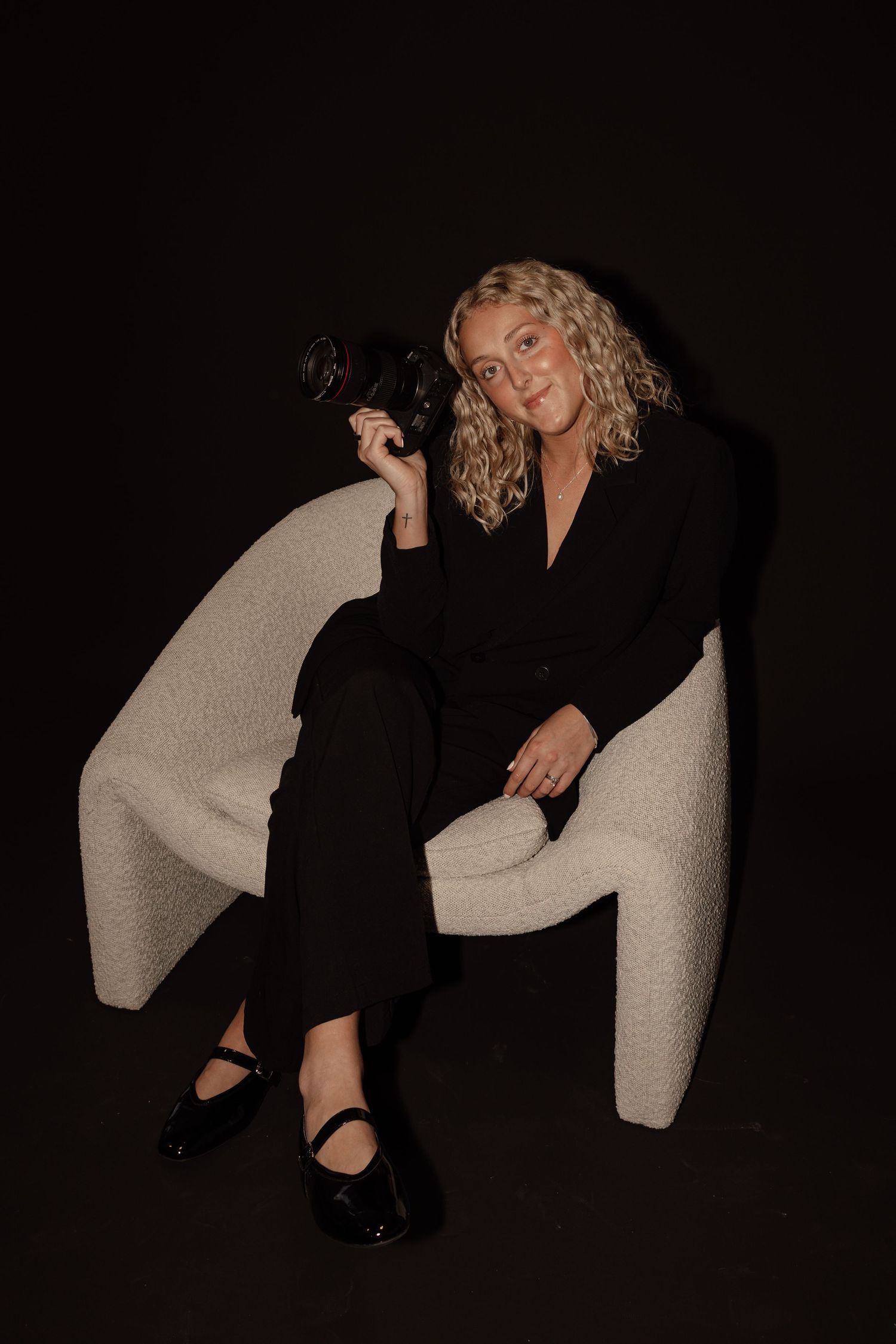 Artistic studio photography featuring a light chair and dark clothing against a black backdrop.