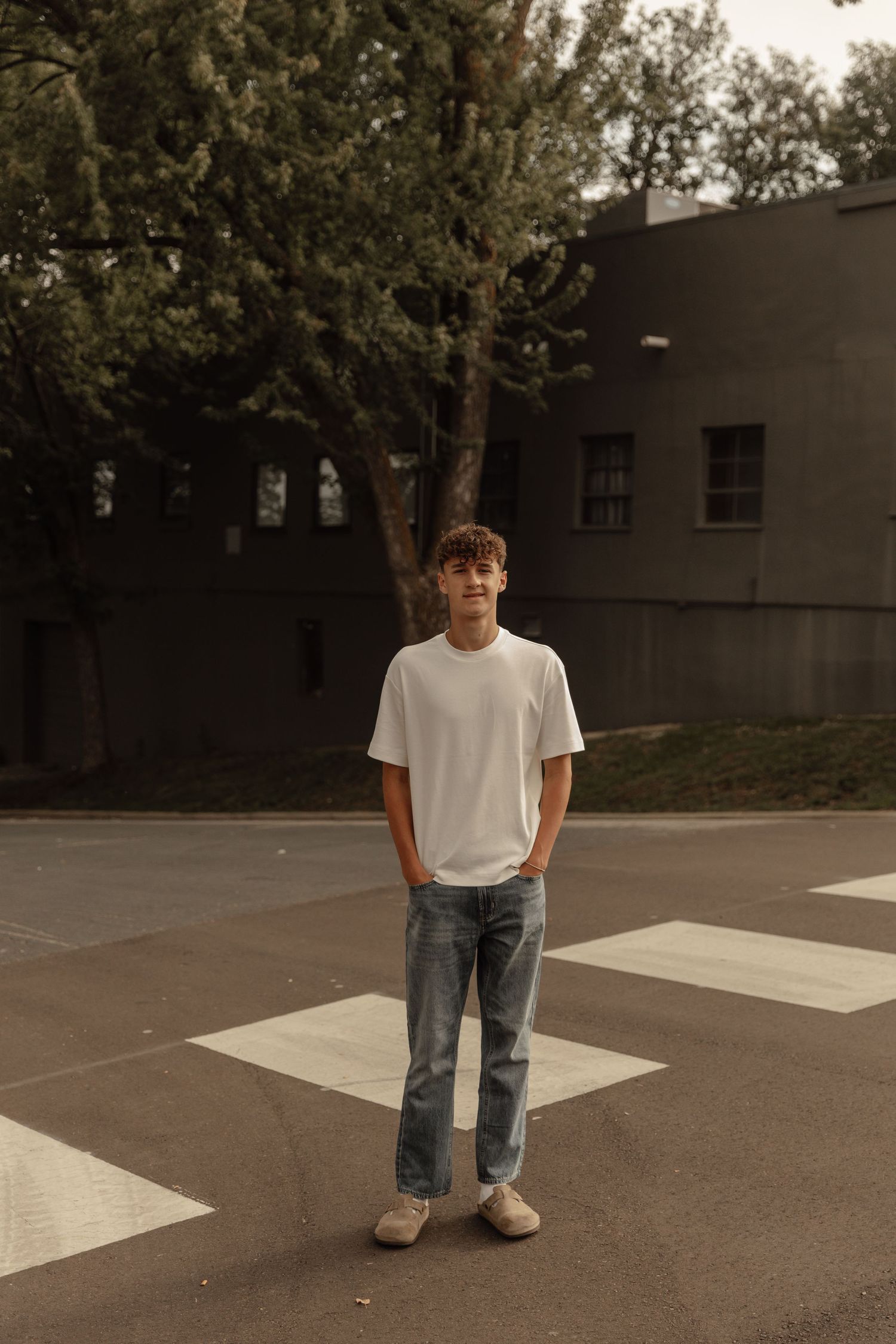 Minimalist portrait of someone standing on a crosswalk wearing casual attire.