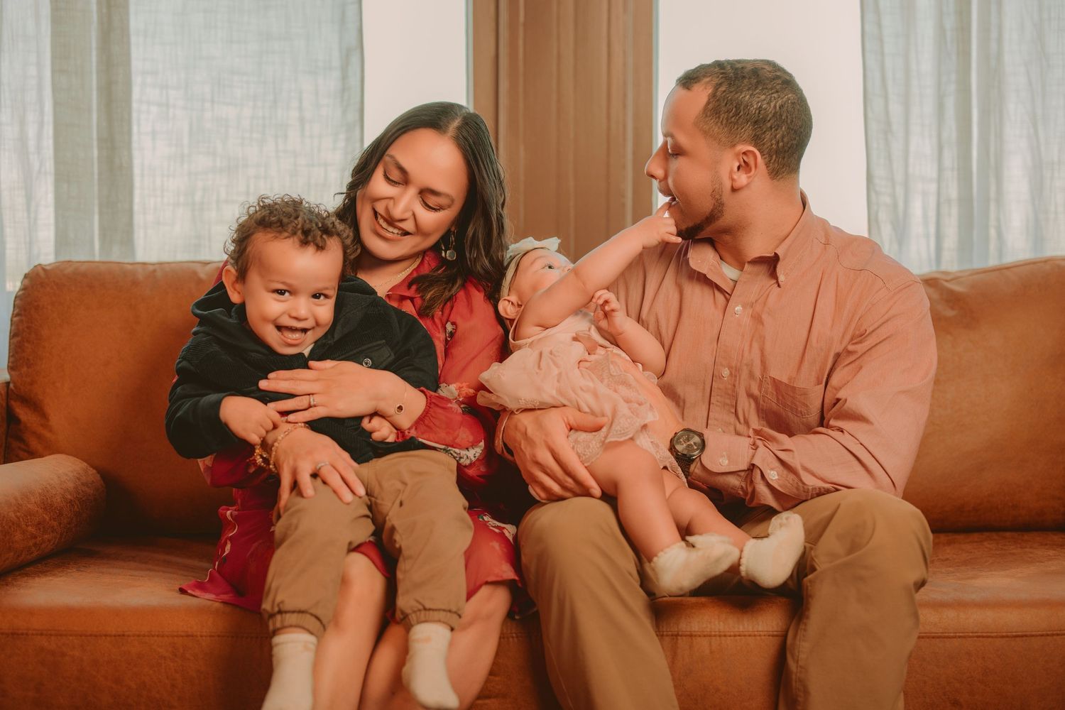 Family members share joyful moments together while relaxing on a cozy brown couch.
