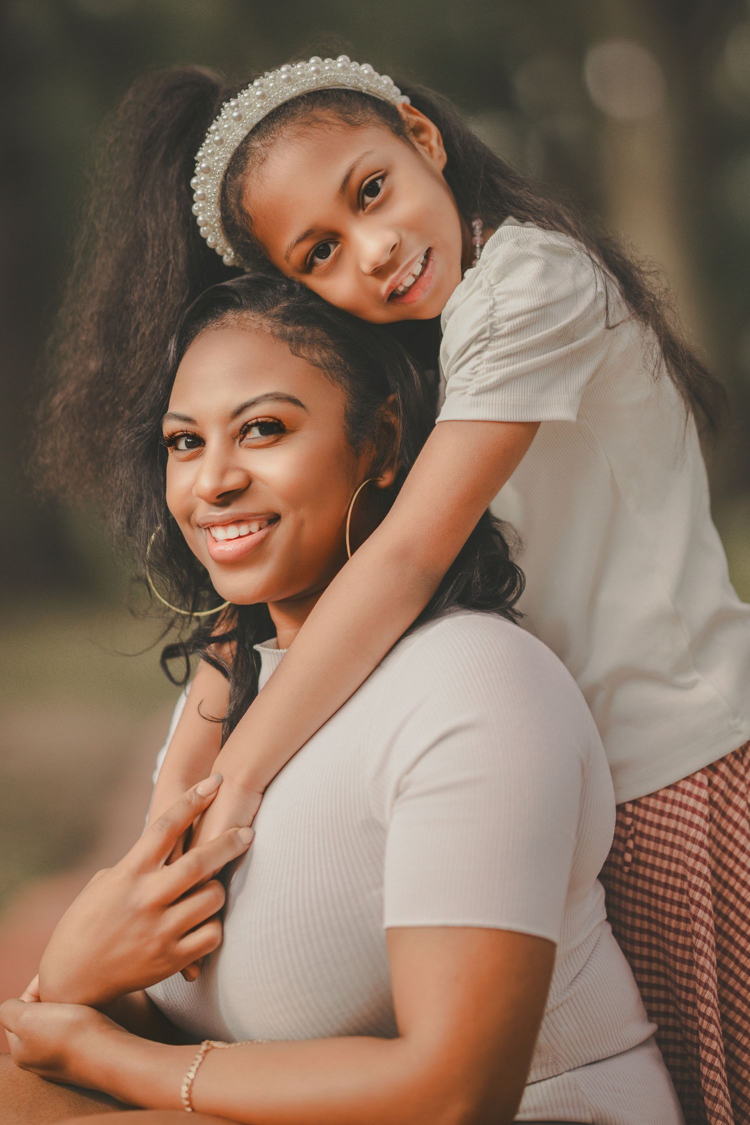 Warm-toned maternity portraits showing intimate moments in white and cream colored outfits against a natural backdrop.