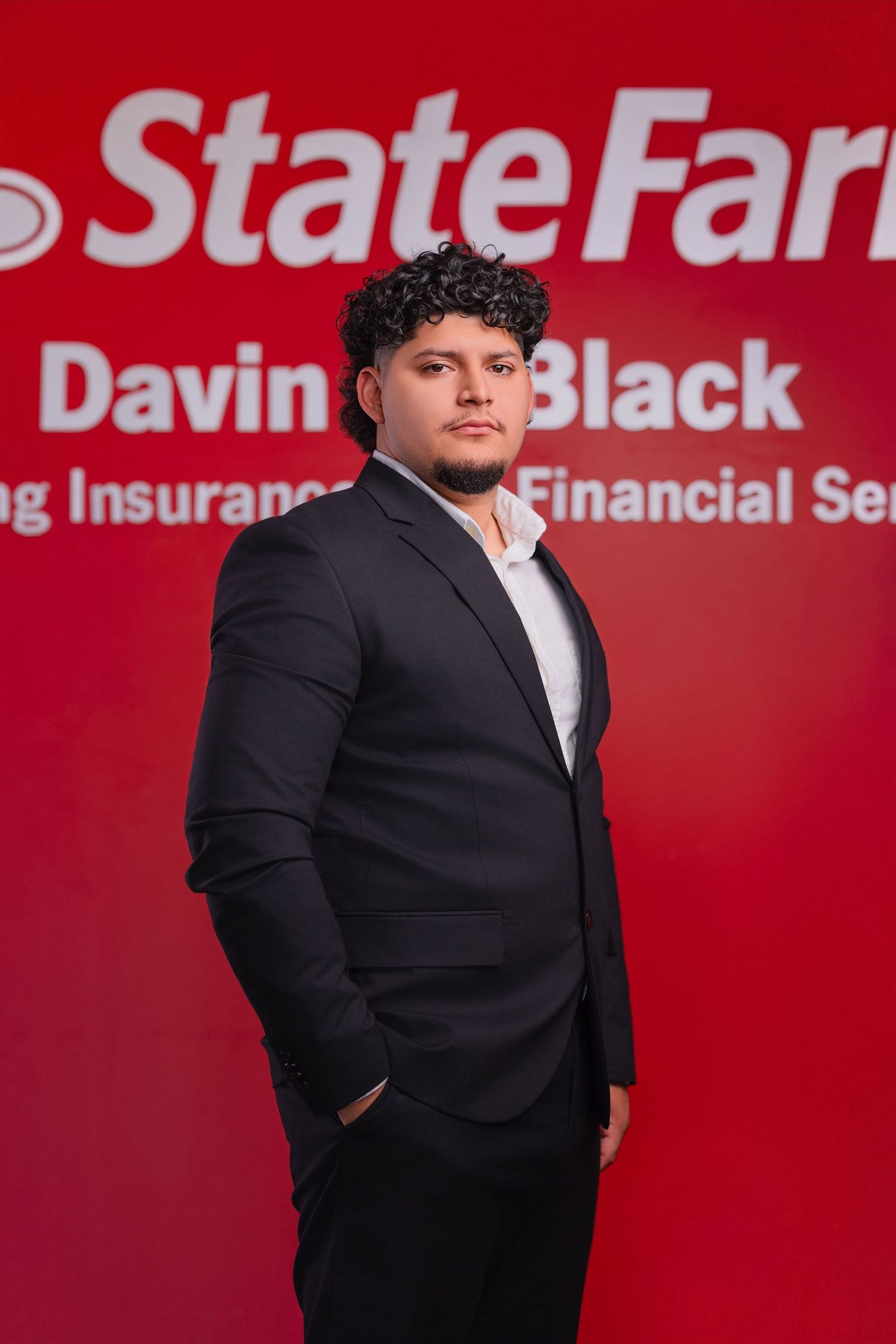 Professional business portrait against red State Farm branded background.