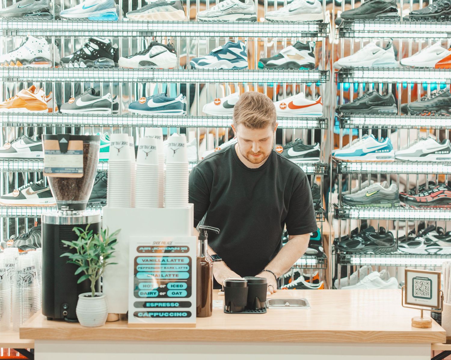 Modern sneaker display wall with multiple shelves showing various athletic shoes in a retail environment.