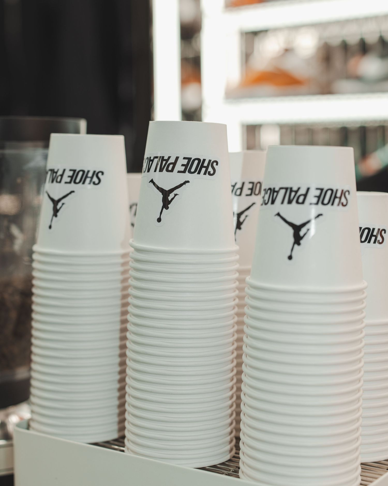 Stacked white paper cups with Jordan brand logos lined up in a retail display.