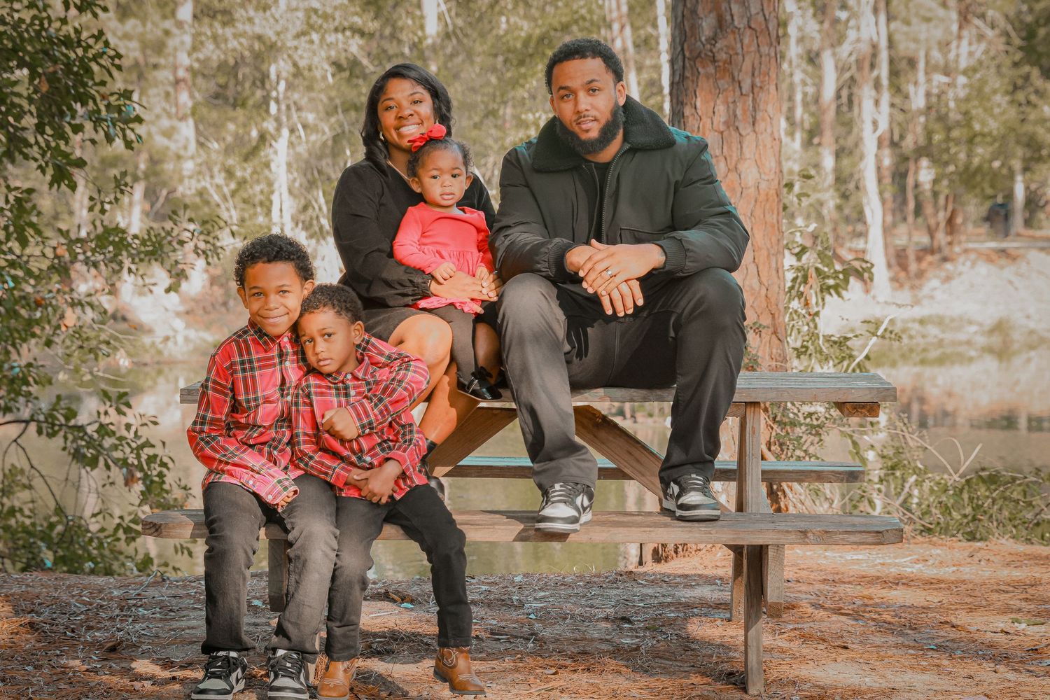 Family photoshoot in a rustic outdoor setting with people sitting on wooden benches.