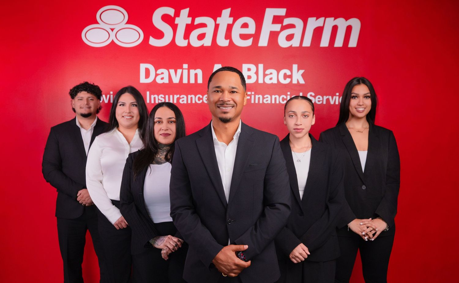 Group photo of insurance team standing against red State Farm backdrop.