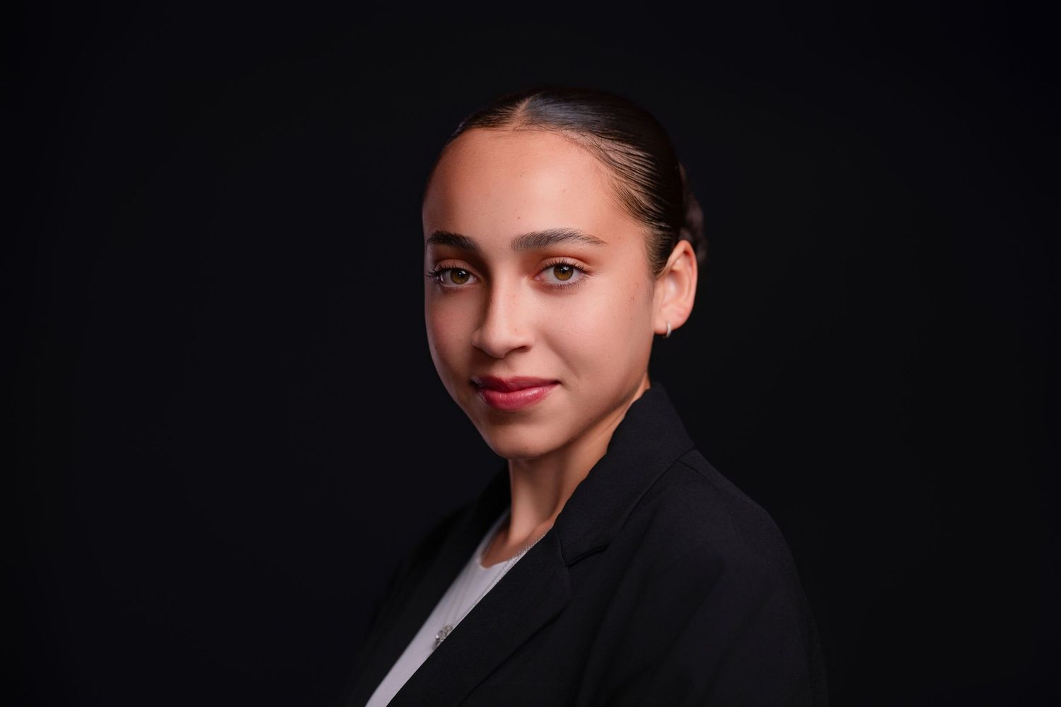 Professional headshot against dark backdrop with business attire.
