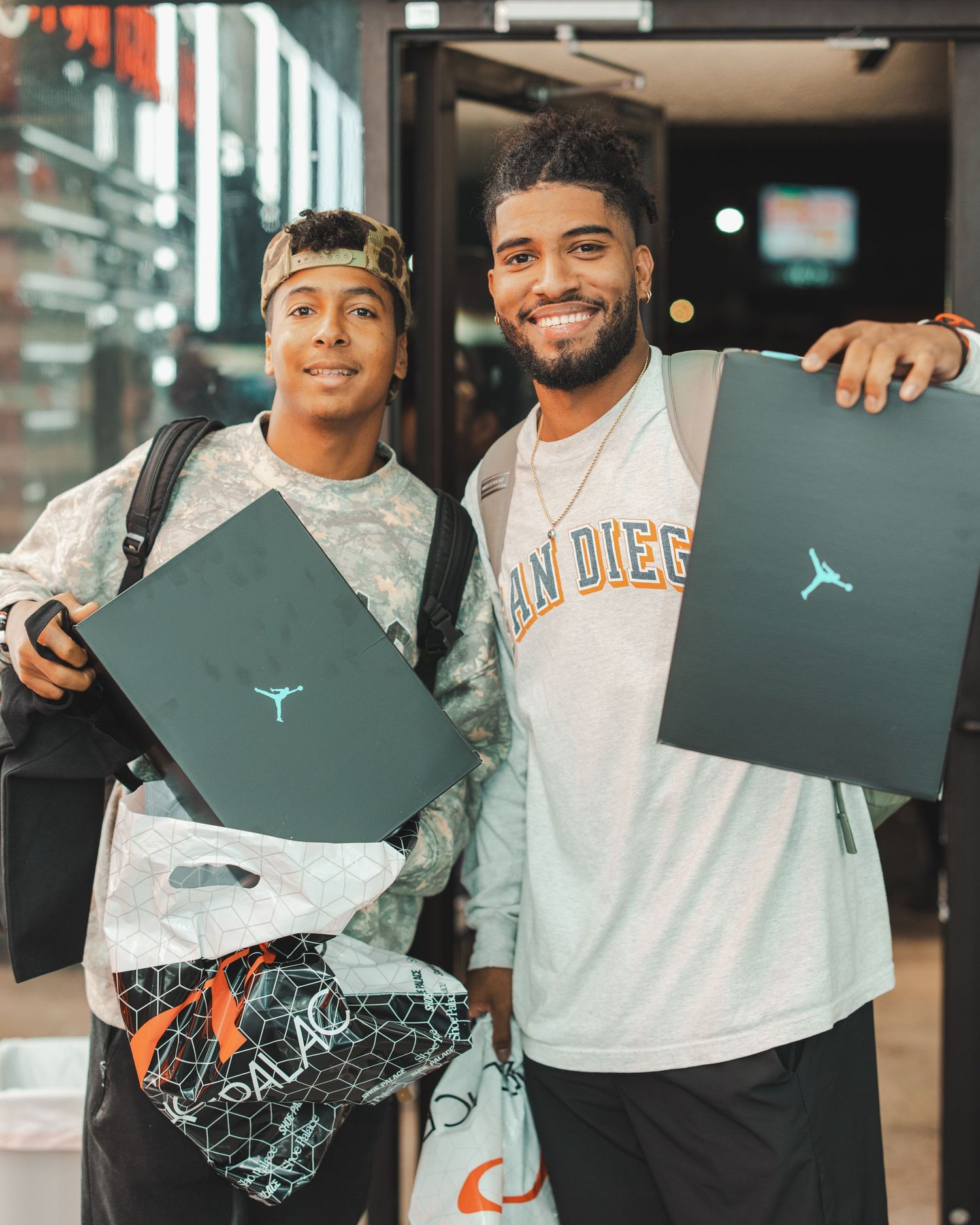 Group of friends showing off their Jordan brand shopping bags at a retail store.