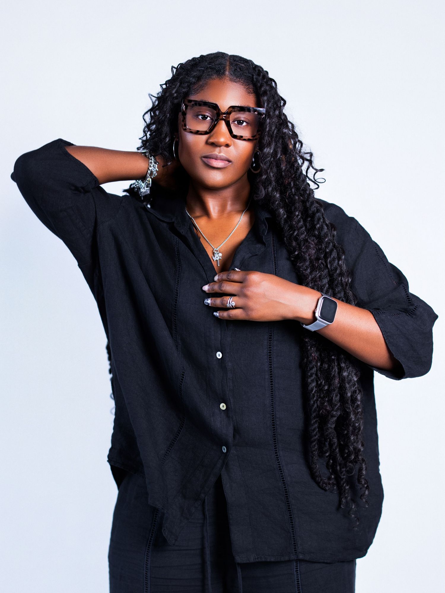Studio portraits featuring black outfit and smartwatch against white background.