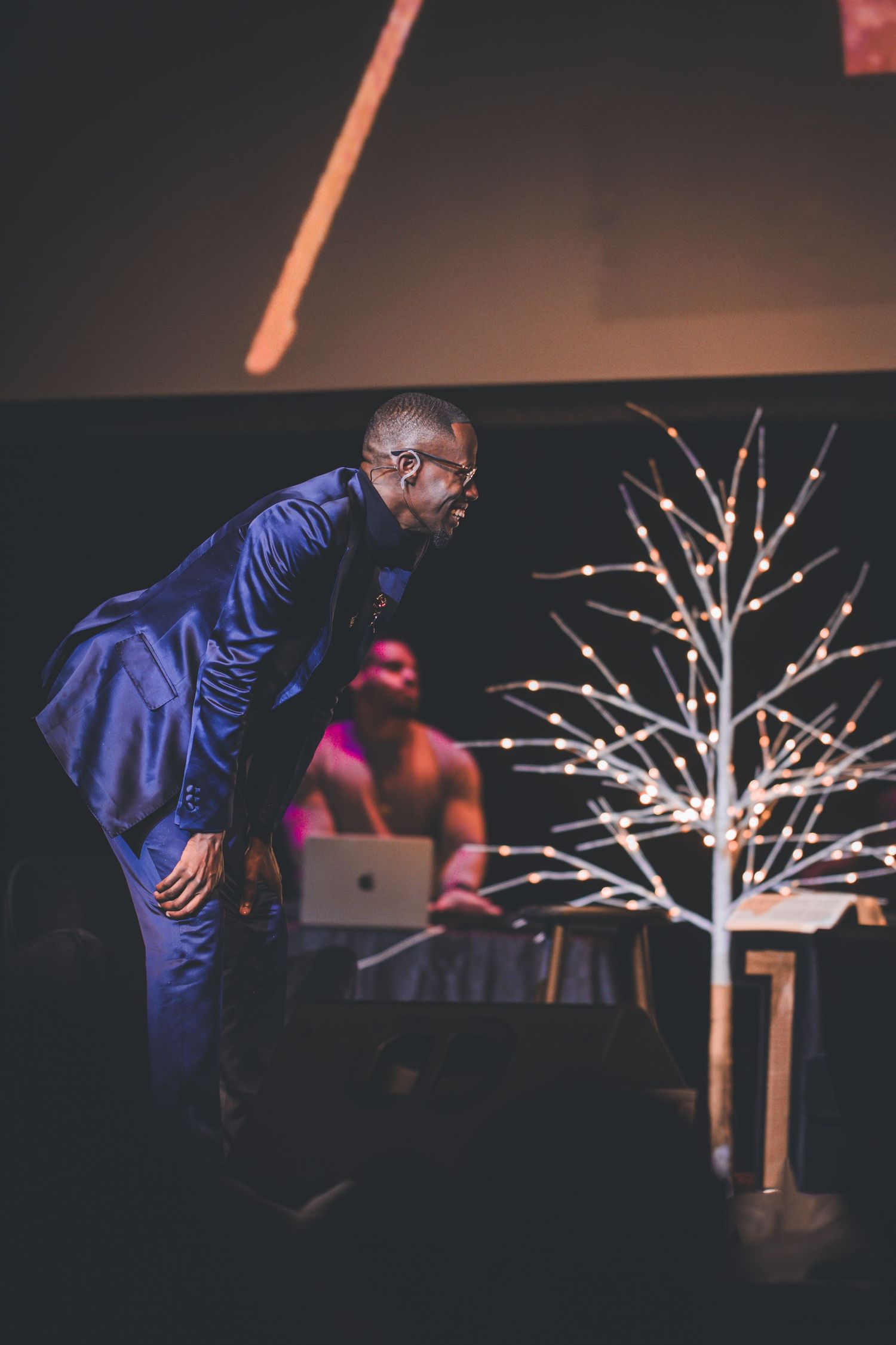 Stage performance with illuminated white tree decorations and dramatic lighting effects.