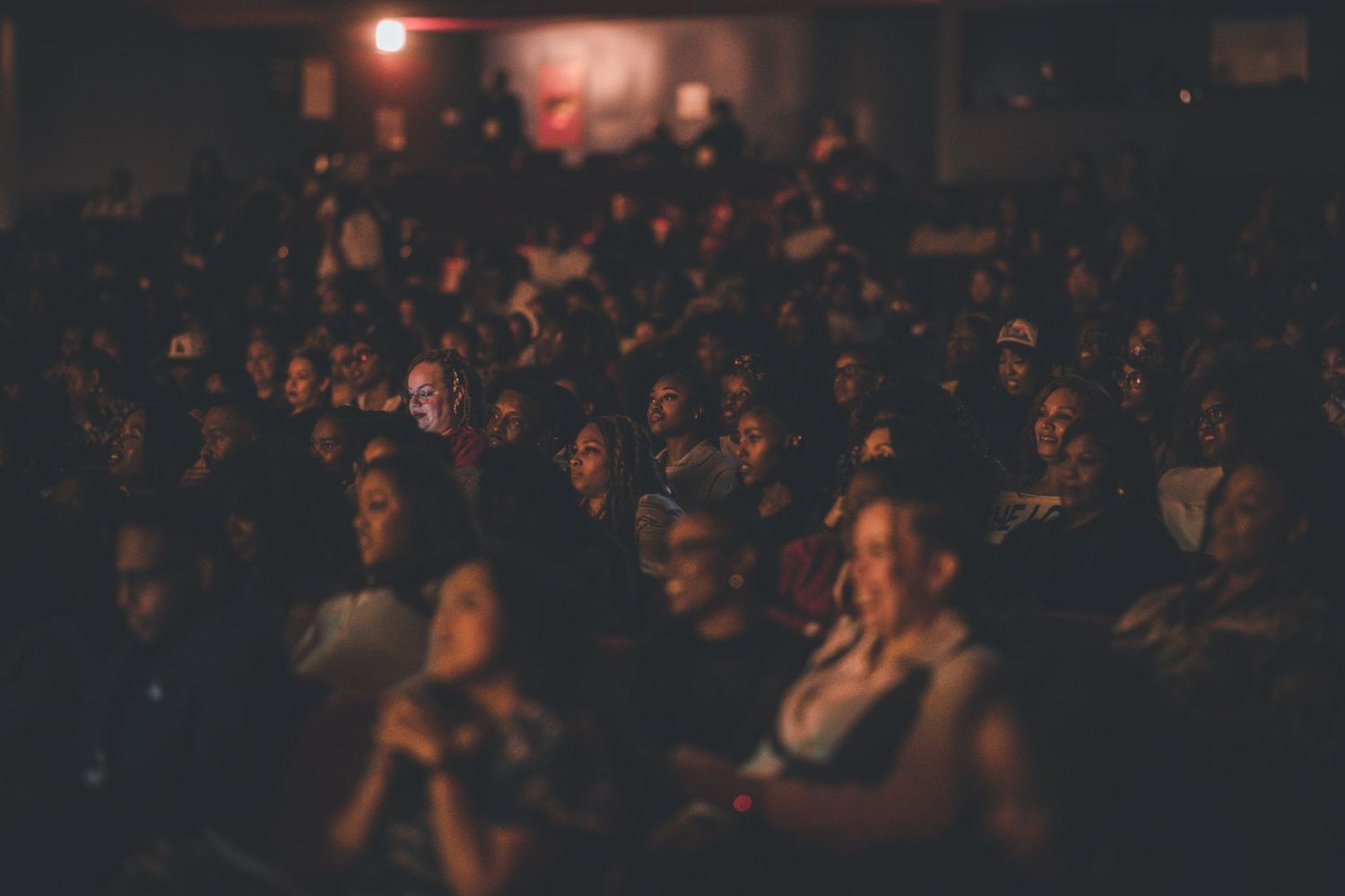Dimly lit audience watching intently during a theater performance.