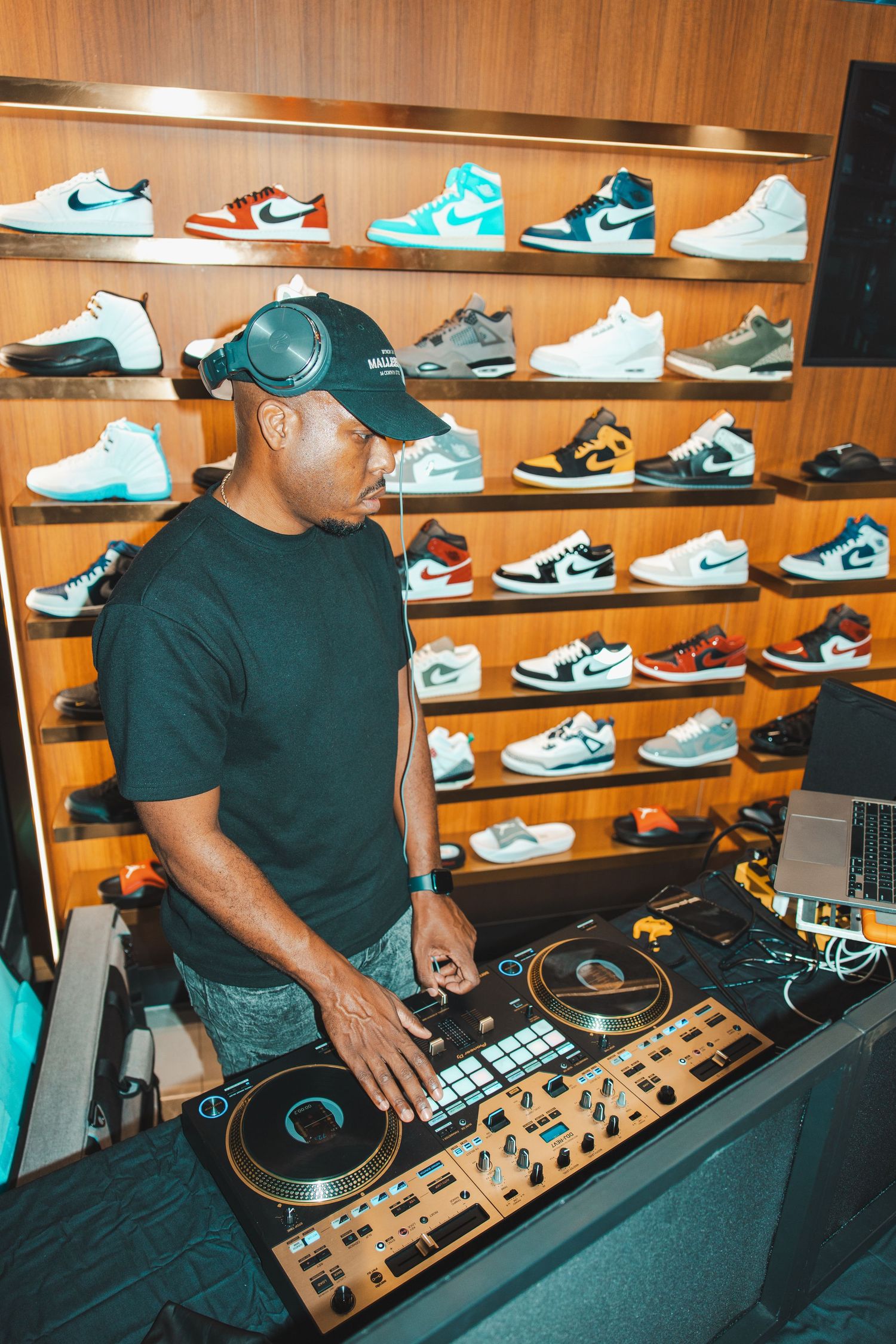 DJ setup with turntables in front of a wall display of Jordan sneakers.