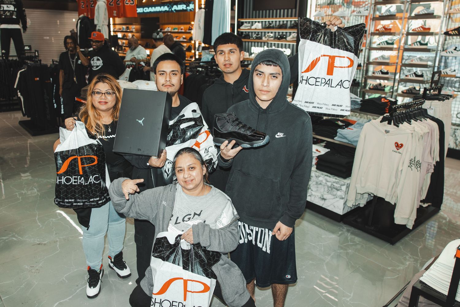 Customers and staff interacting inside sneaker store with display shelves.