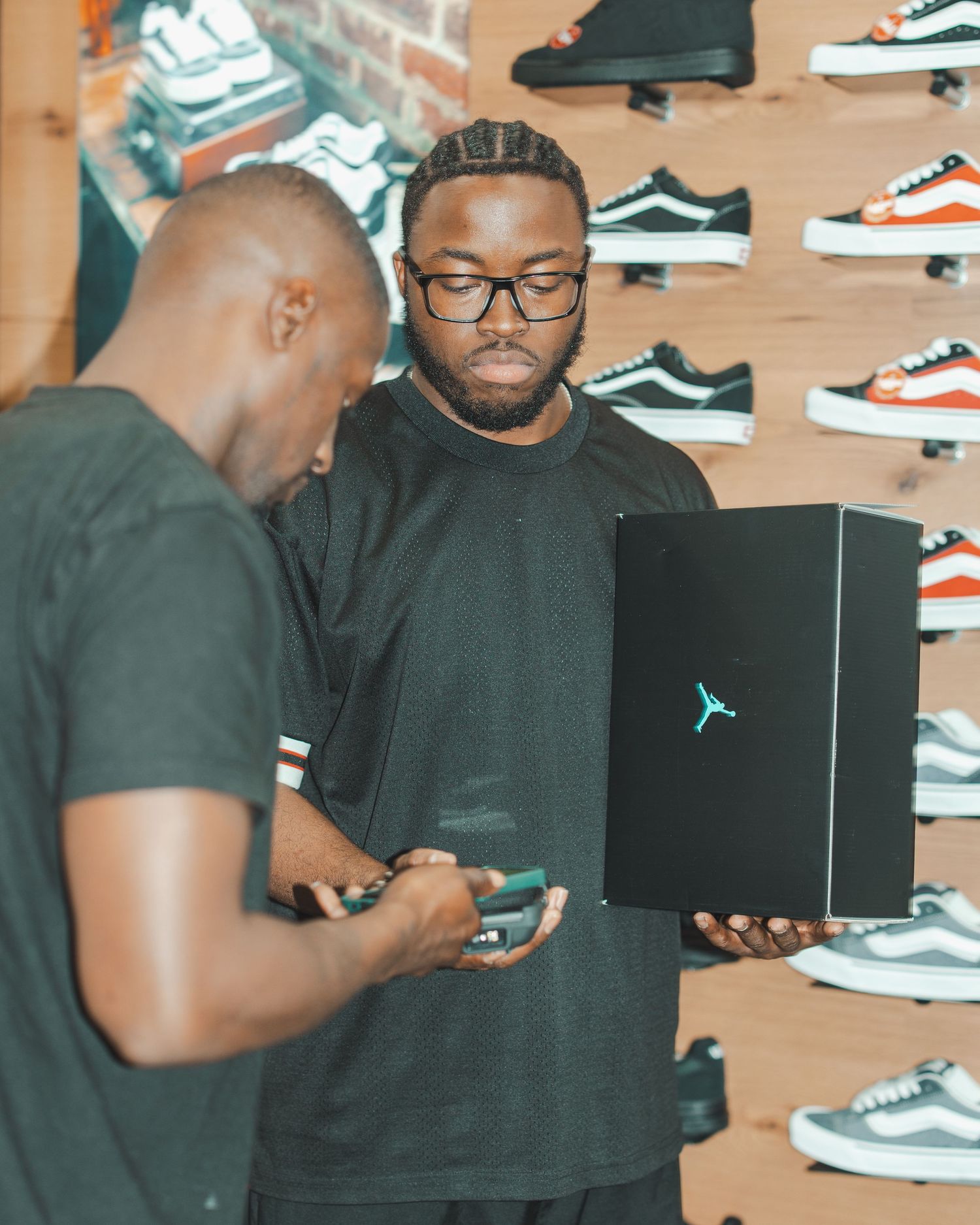 Customers examining Jordan brand shoe boxes in a sneaker store.