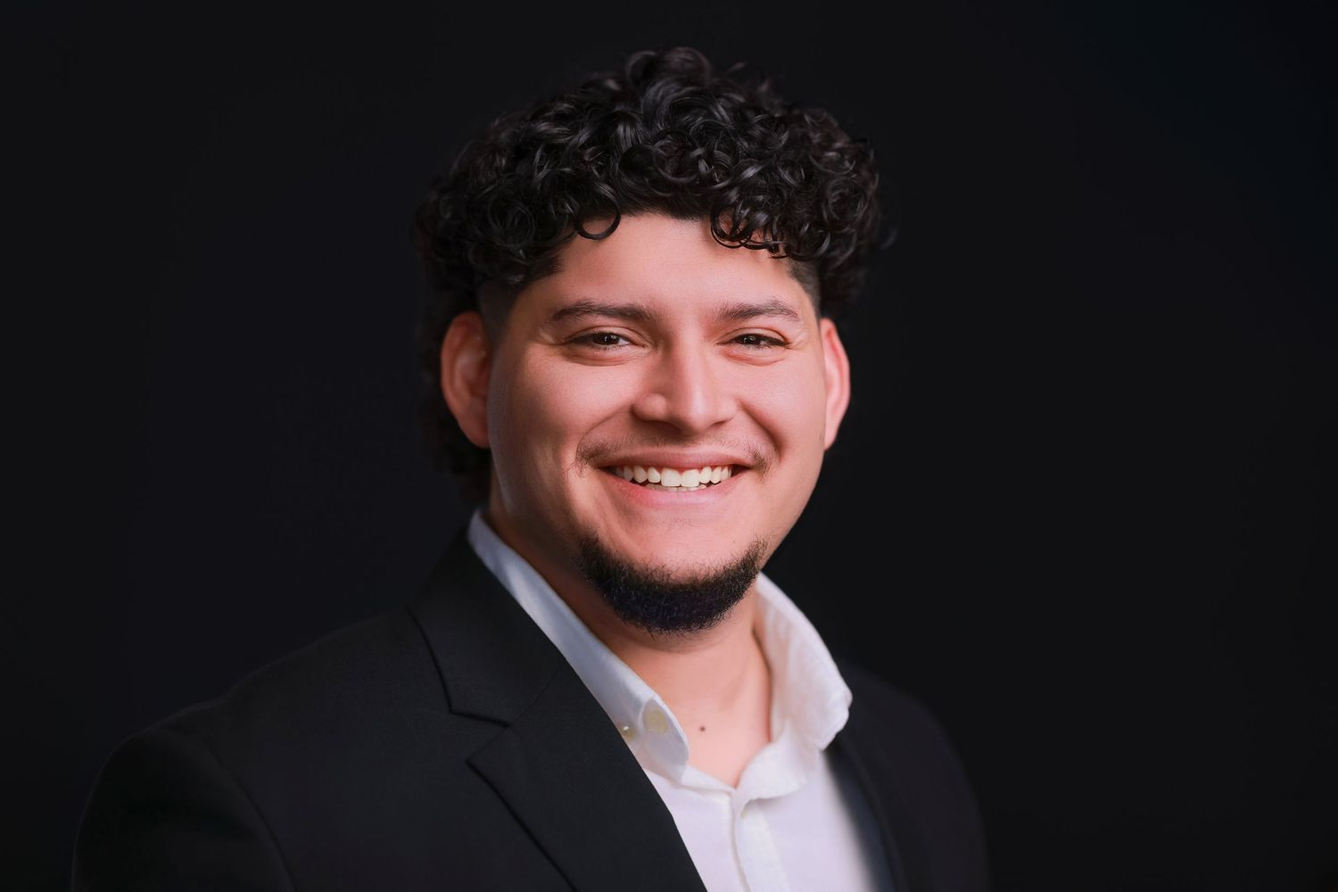 Professional headshot portrait session against dark background with dramatic lighting.