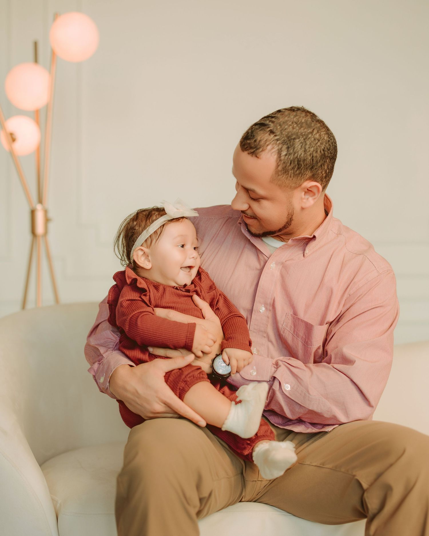 Parent and child share tender moments while sitting together on a couch in a warm-toned minimalist setting.