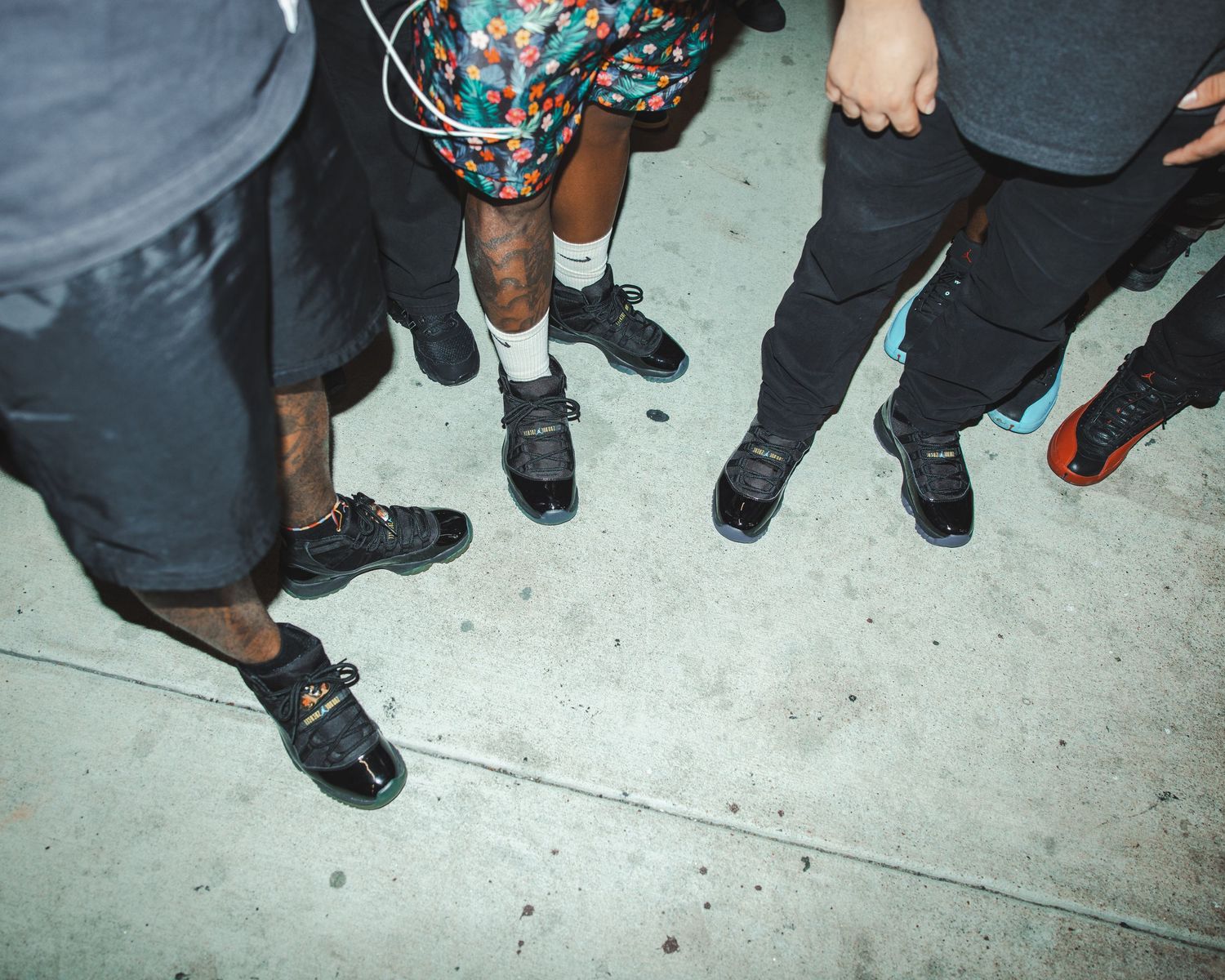 Close-up shot of colorful sneakers and feet of people gathered in a group.