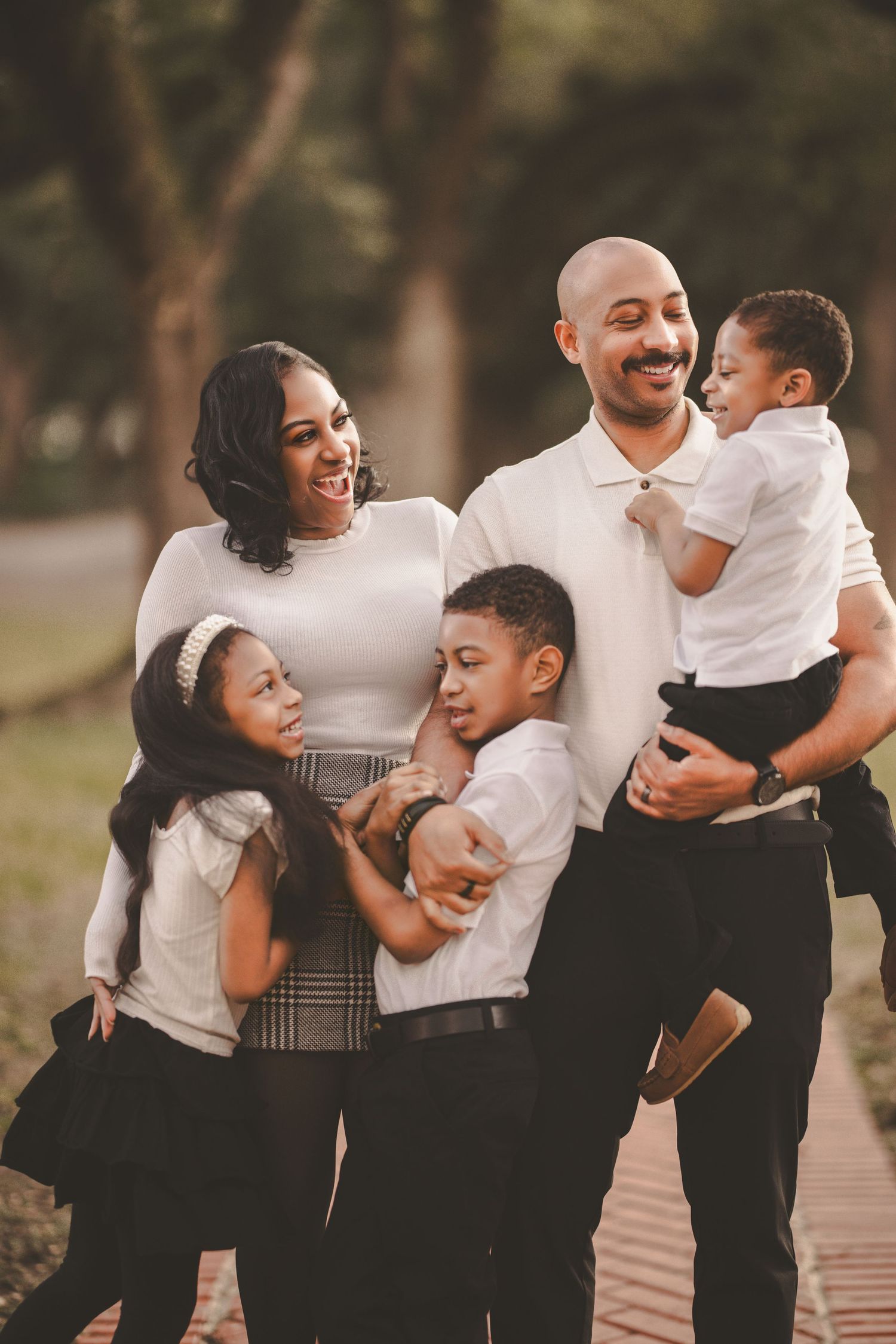A joyful family wearing coordinated black and white outfits shares candid moments together during an outdoor photo session.