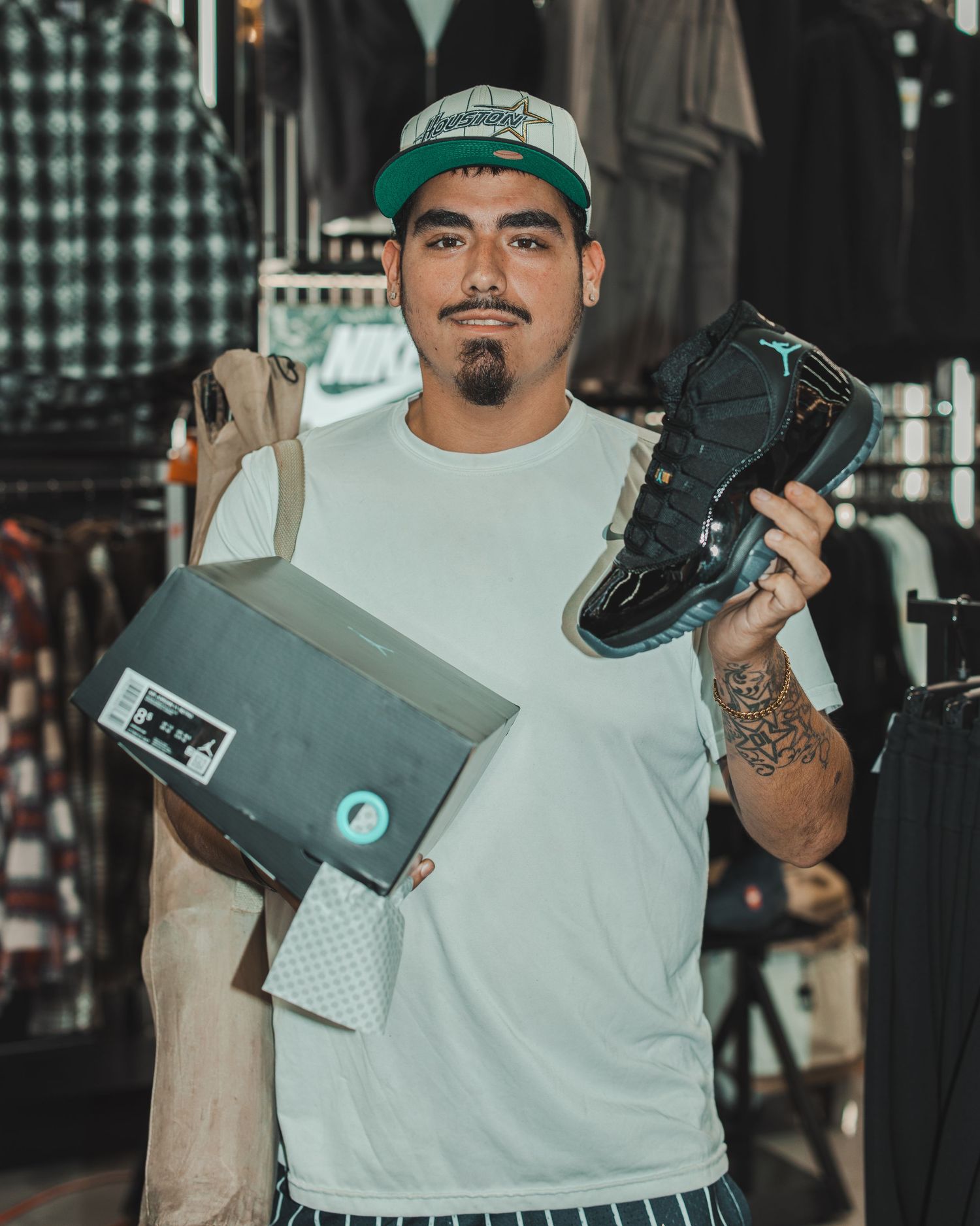 Customer holding shoe boxes and displaying purchases at sneaker store.