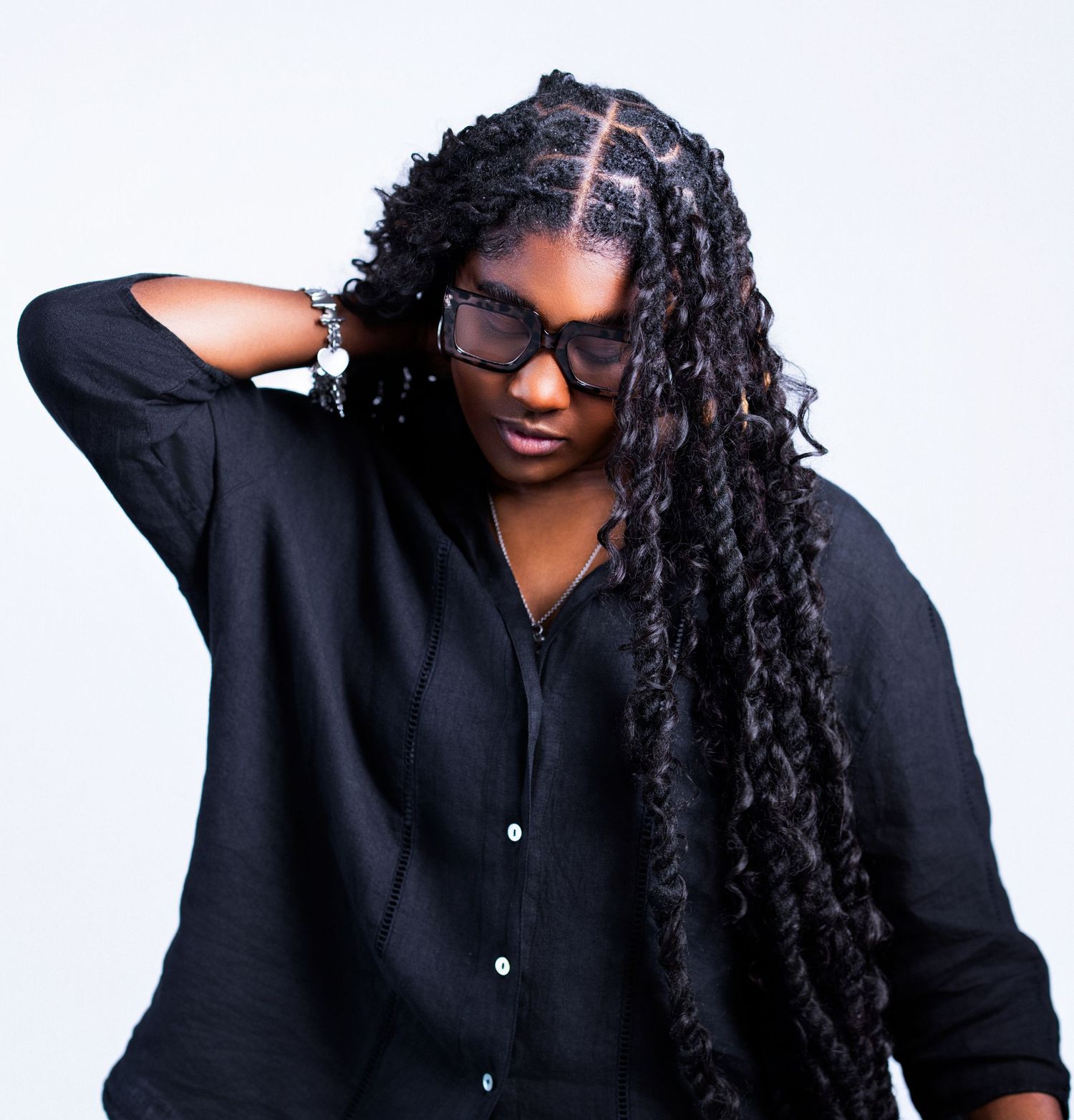 Artistic headshots with flowing curls and glasses against minimalist white backdrop.