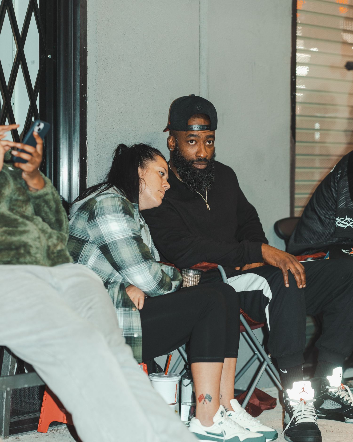 Group sitting together in casual setting with dim lighting and streetwear outfits.
