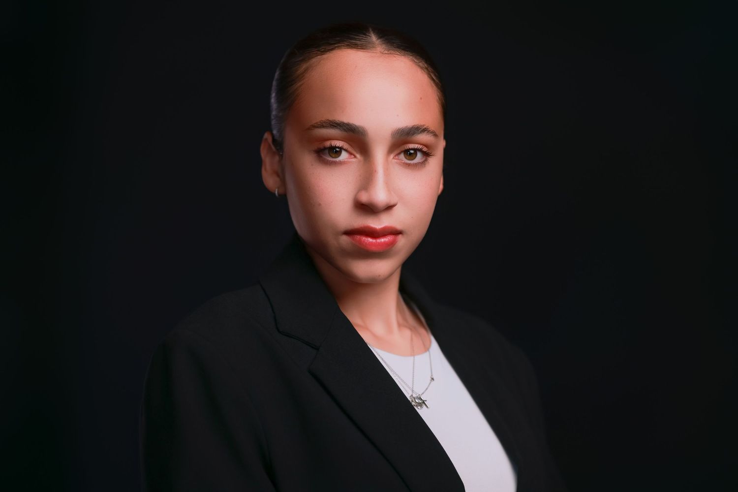 Studio portrait with dramatic lighting against black background.