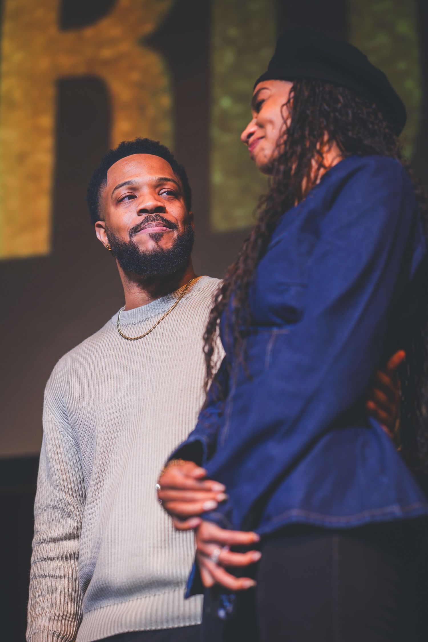 Two performers share an intimate moment on stage during a live performance.