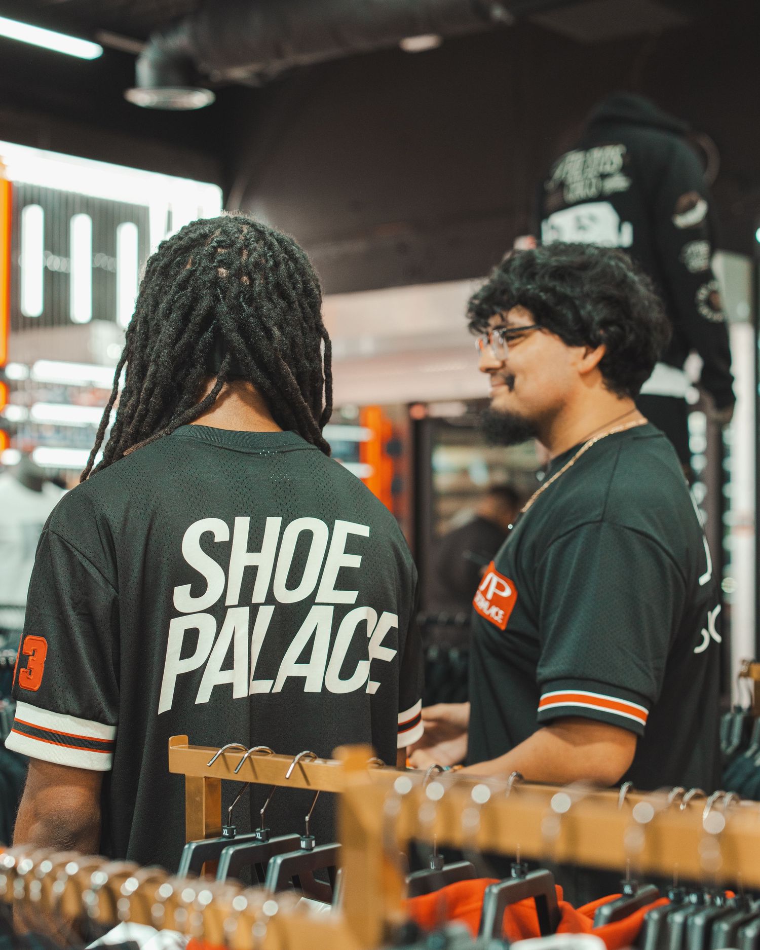 Staff members wearing black Shoe Palace branded t-shirts working in a retail environment.