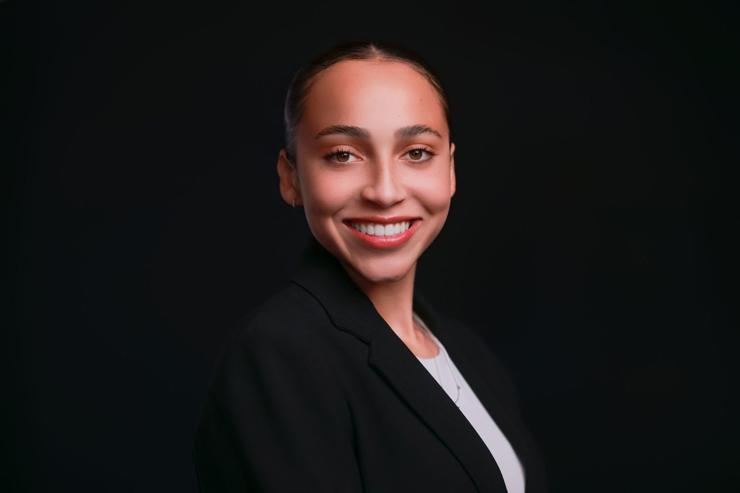 Professional portrait with bright smile against dark backdrop.